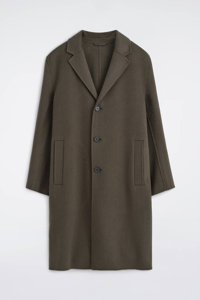 The Tailored Double-Faced Wool-Blend Coat is hanging facing the front, showcasing a dark olive green colour, notch lapels, and a single-breasted three-button fastening. It features vertical welt pockets on each side and long sleeves, presenting a clean, structured silhouette. - 1