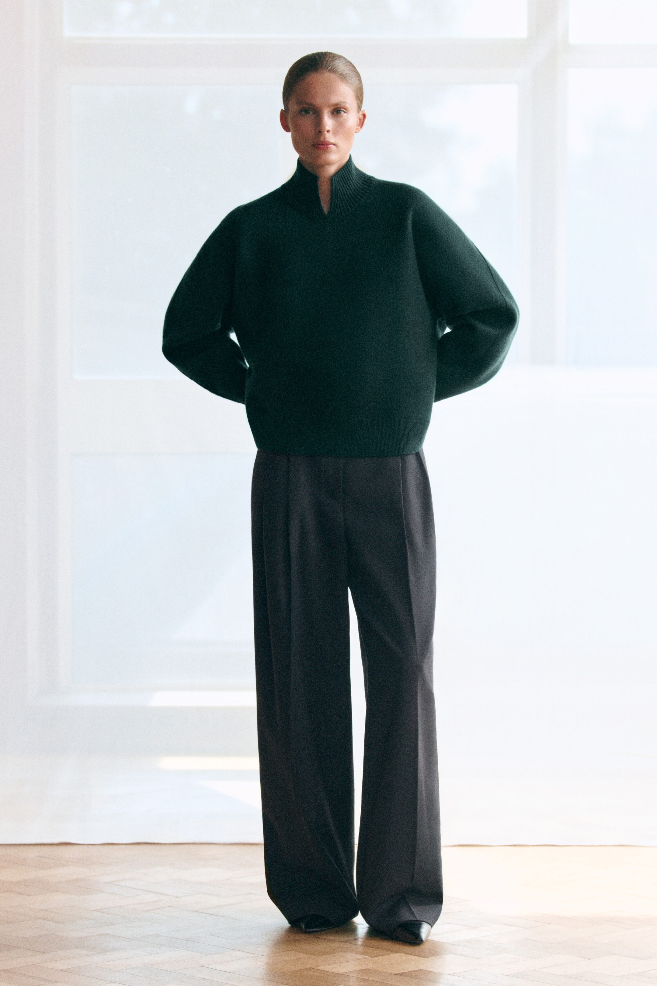 Le pull col montant en laine bouillie vert foncé est présenté de face, avec une coupe décontractée, des épaules tombantes et un col côtelé orné d’un petit détail d’encolure en V. Le pull est stylé avec un pantalon sombre à jambe large, mettant en valeur son tombé doux et structuré. Le pull col montant en laine bouillie vert foncé est présenté de face, avec une coupe décontractée, des épaules tombantes et un col côtelé orné d’un petit détail d’encolure en V. Le pull est stylé avec un pantalon sombre à jambe large, mettant en valeur son tombé doux et structuré.