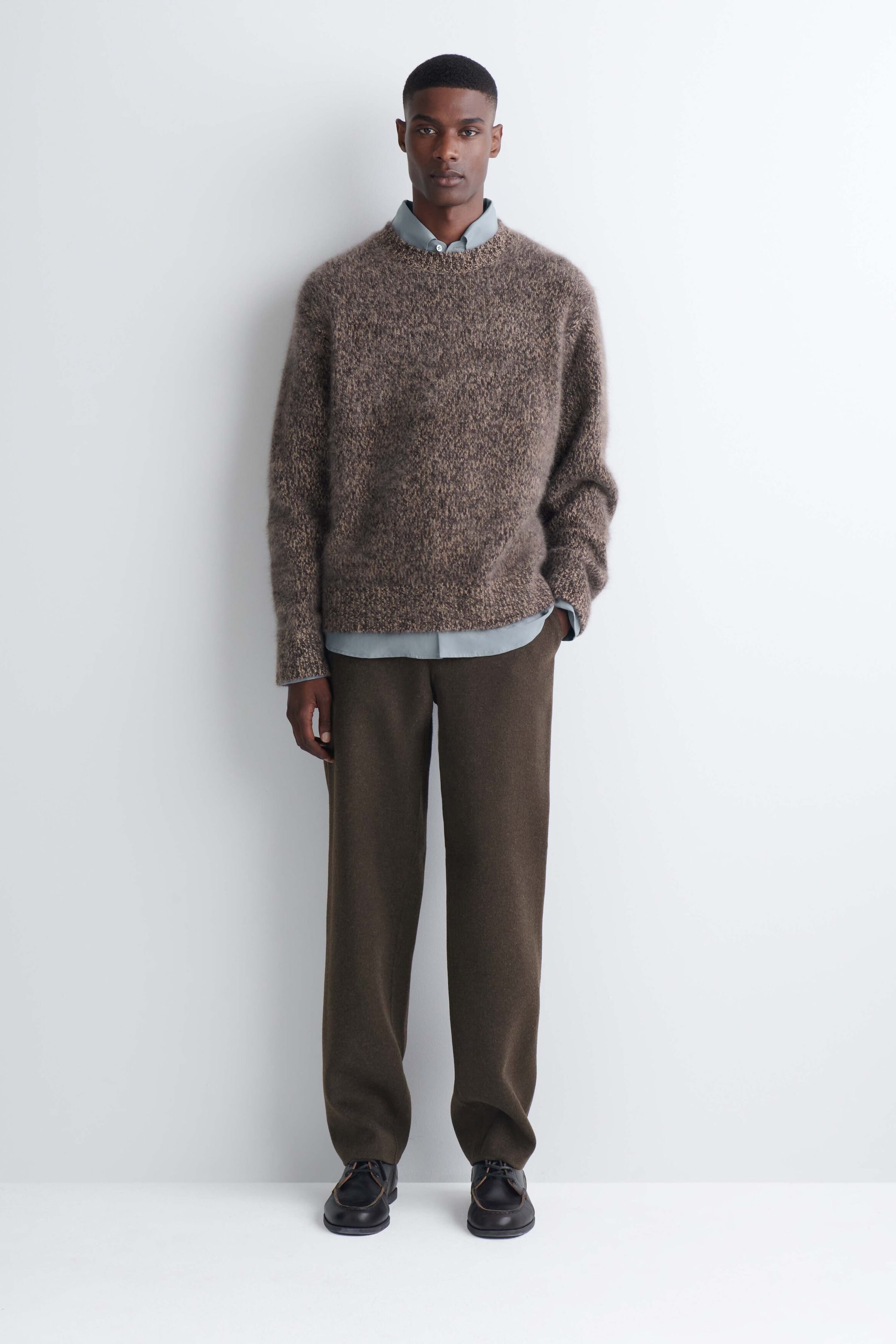 Double-faced wool-blend straight-leg pants in dark brown are worn by the model, who is standing with one hand resting in a side pocket. The relaxed-fit pants are styled with a textured brown crewneck sweater, a light blue collared shirt, and dark leather shoes. Double-faced wool-blend straight-leg pants in dark brown are worn by the model, who is standing with one hand resting in a side pocket. The relaxed-fit pants are styled with a textured brown crewneck sweater, a light blue collared shirt, and dark leather shoes.