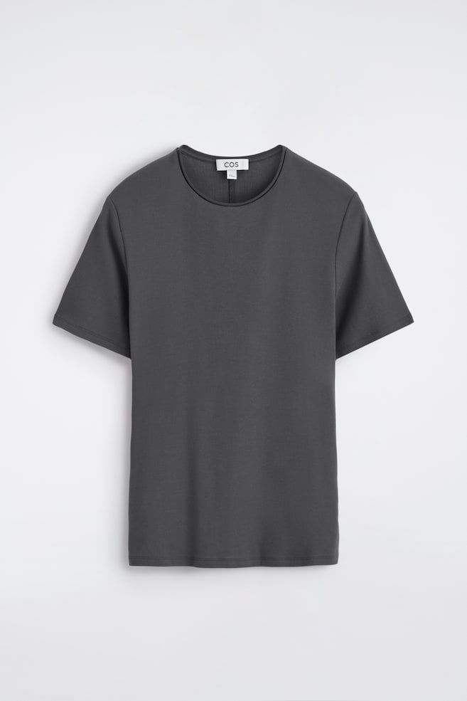 A dark grey T-shirt is displayed front-facing, showcasing its slim fit. It features a rolled crew neckline and short sleeves, with twin-needle topstitching finishing the hem and sleeve cuffs. - 1