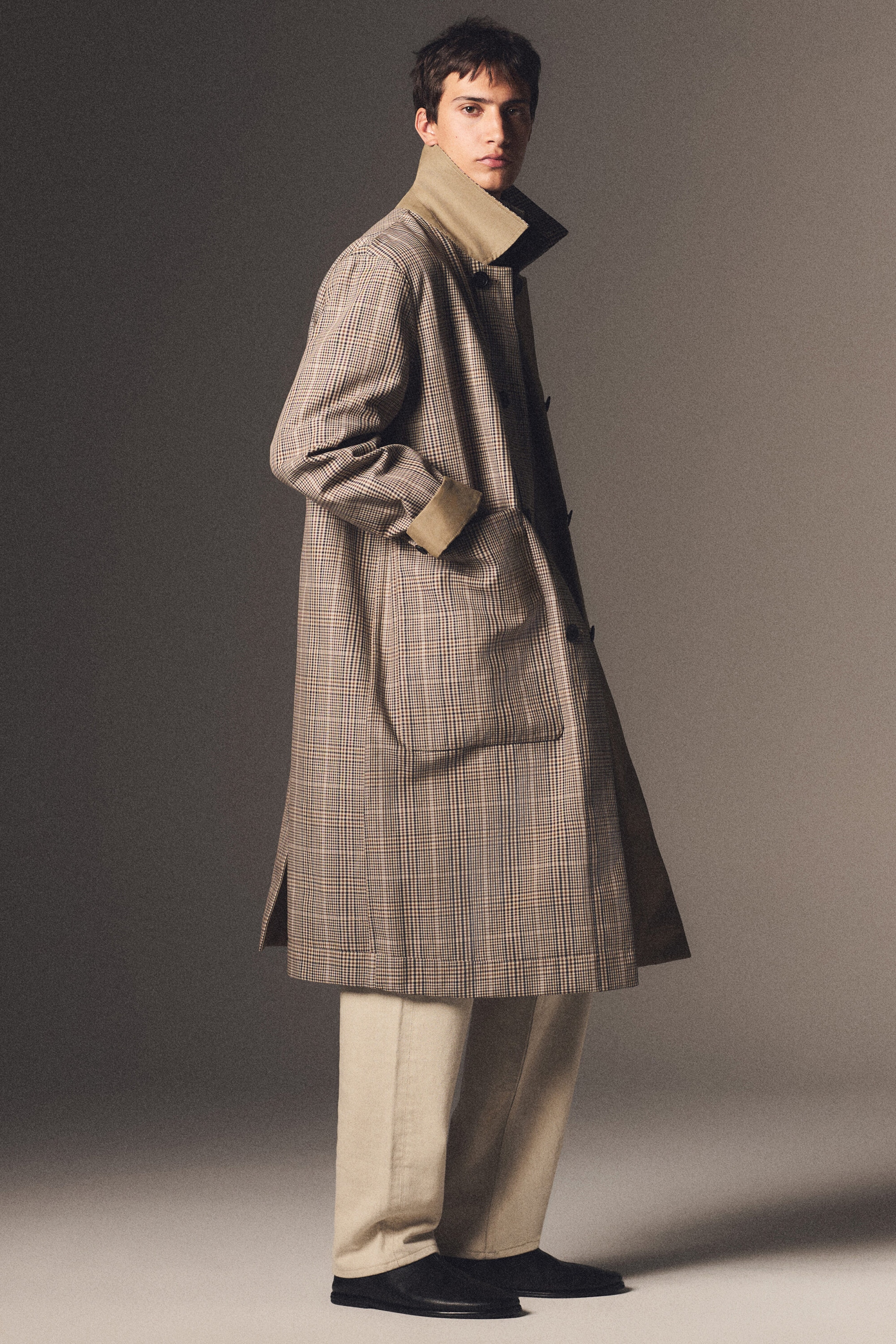 Le manteau automobile réversible à carreaux est présenté en vue trois quarts de côté, mettant en valeur sa coupe décontractée, son ourlet longueur genou et son motif à carreaux marron et beige. Il présente un col montant haut et des poignets retroussés révélant une doublure beige unie, ainsi qu’une grande poche plaquée sur le devant. Le manteau automobile réversible à carreaux est présenté en vue trois quarts de côté, mettant en valeur sa coupe décontractée, son ourlet longueur genou et son motif à carreaux marron et beige. Il présente un col montant haut et des poignets retroussés révélant une doublure beige unie, ainsi qu’une grande poche plaquée sur le devant.