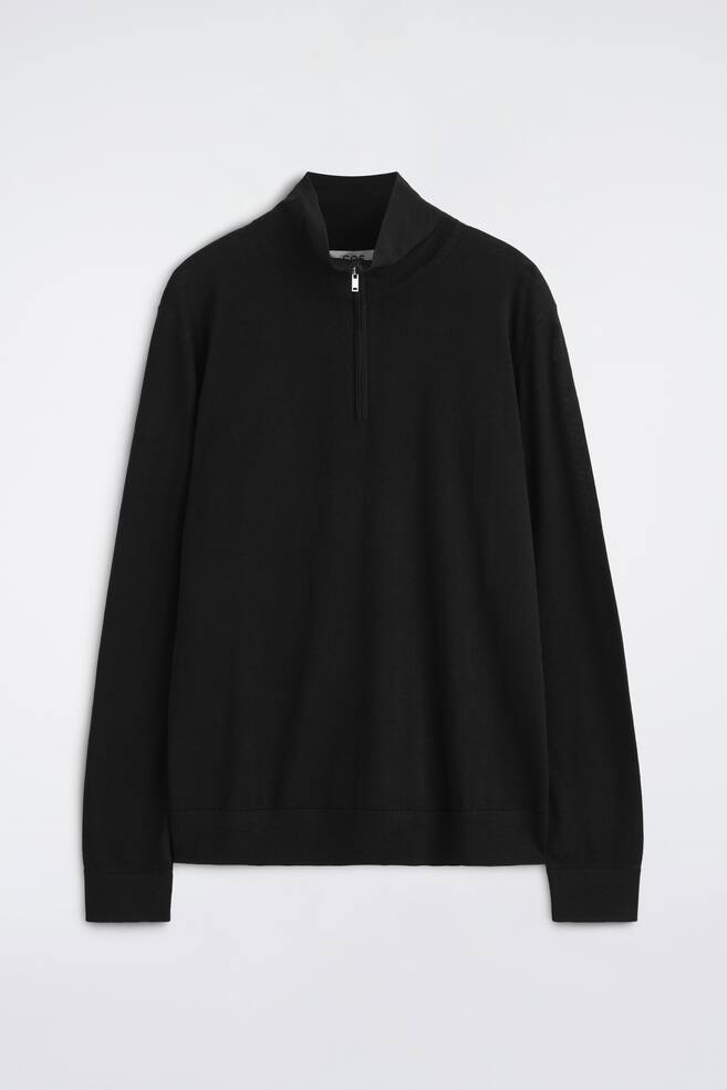 Der schwarze Merinowoll-Pullover mit ReiÃverschluss und Stehkragen ist von vorne zu sehen und verfÃ¼gt Ã¼ber einen hohen Kragen mit halbierendem ReiÃverschluss in Silberoptik. Das langÃ¤rmelige KleidungsstÃ¼ck zeigt gerippte BÃ¼ndchen und einen passenden gerippten Saum. - 1