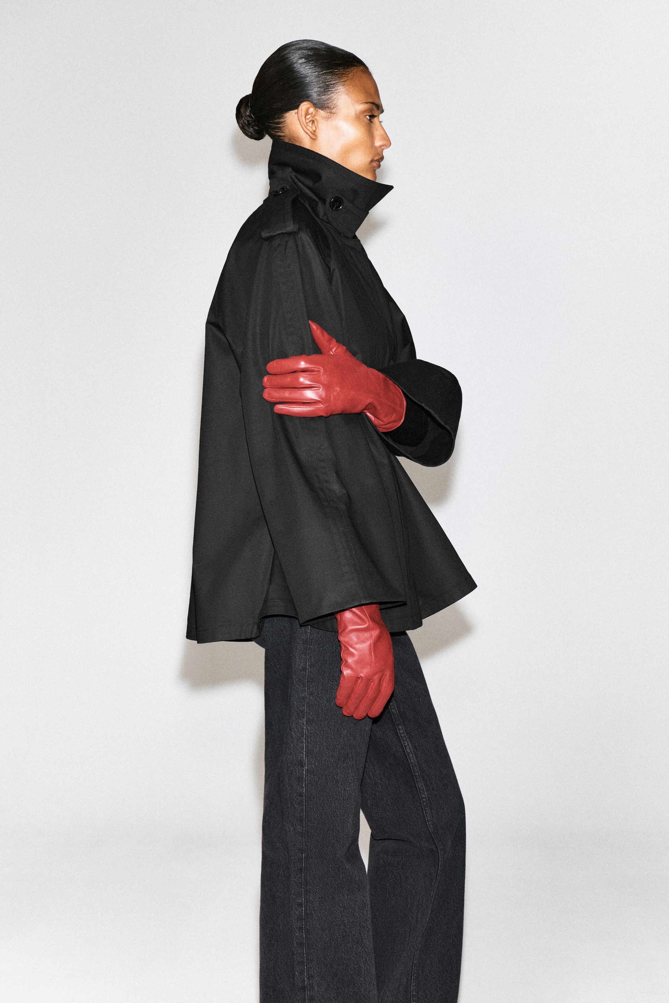 Le mannequin porte des gants en cuir rouge et repose une main sur la manche d’une veste noire à col montant, assortie à un jean gris foncé. Le mannequin porte des gants en cuir rouge et repose une main sur la manche d’une veste noire à col montant, assortie à un jean gris foncé.