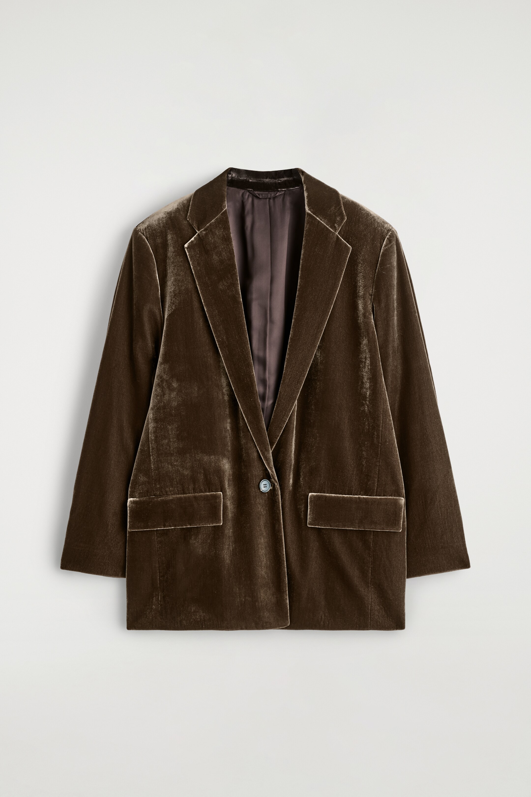 Agrandir l'image: Un blazer en velours marron est présenté de face, avec des revers à cran, une fermeture à un bouton bleu clair et deux poches plaquées à l'avant.