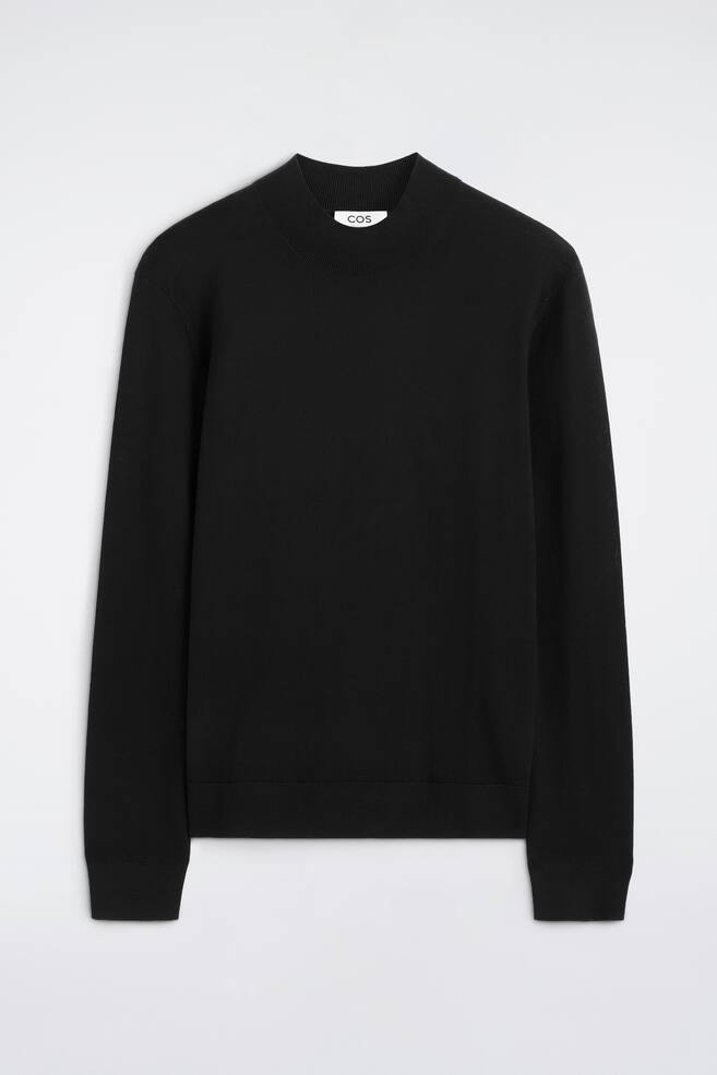 En svart smal jumper i merinoull med mock neck visas framifrÃ¥n och har en ribbad mockkrage, lÃ¥nga Ã¤rmar med ribbade muddar samt en matchande ribbad nederkant. Jumpersen har en slÃ¤t, fint stickad textur och en strukturerad, klassisk silhuett. - 1