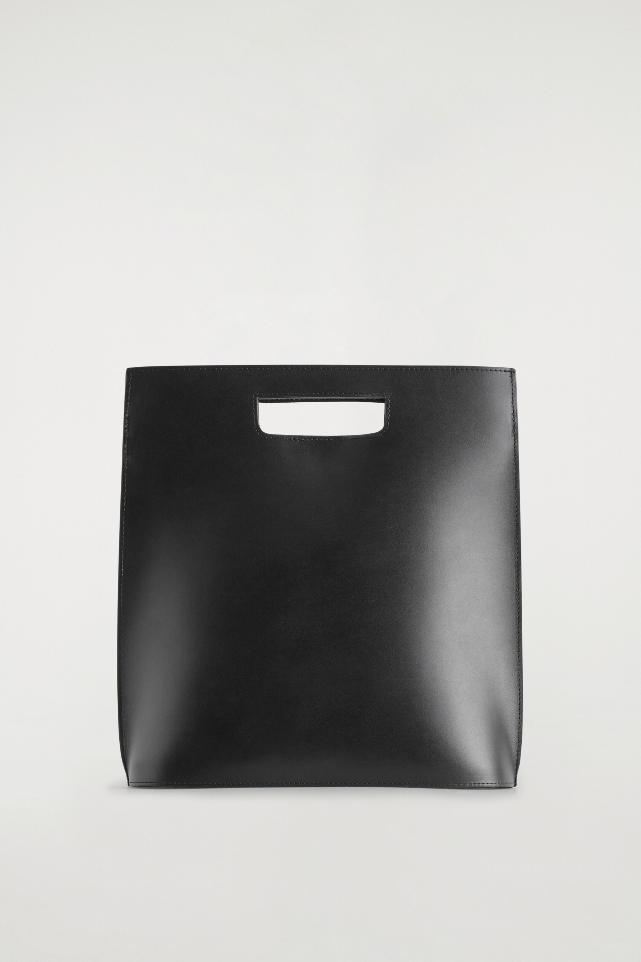Agrandir l'image: Le sac Folio noir est présenté de face, arborant une forme rectangulaire fabriquée en cuir lisse. Il présente une poignée découpée en haut et des bords cousus visibles.