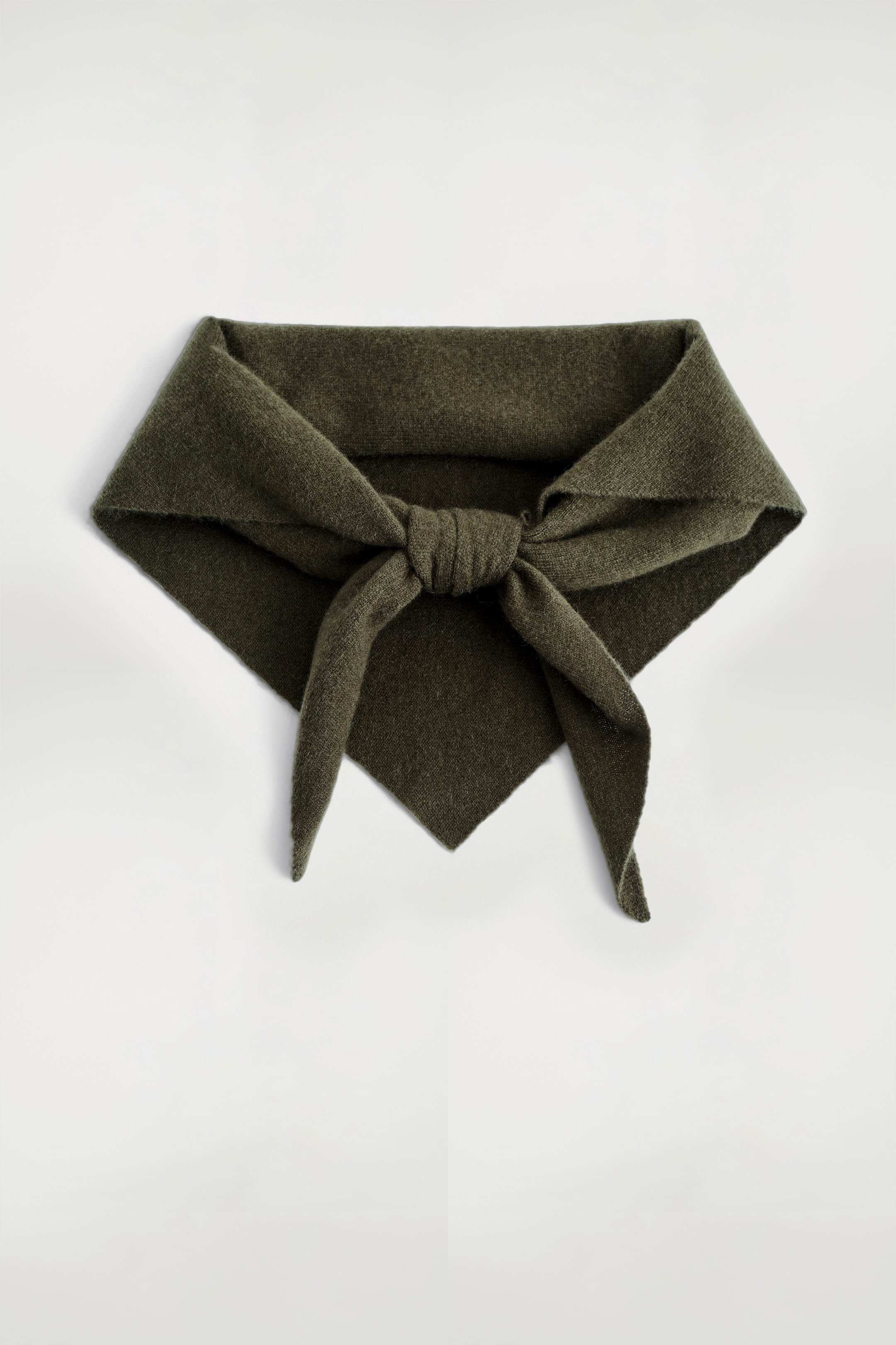 Visualizza immagine più grande: Una sciarpa triangolare verde oliva scuro, con una texture morbida e pelosa visibile, è distesa piatta, presentata con il bordo superiore ripiegato e le sue due estremità strette annodate in un nodo centrale, creando una silhouette triangolare distintiva.