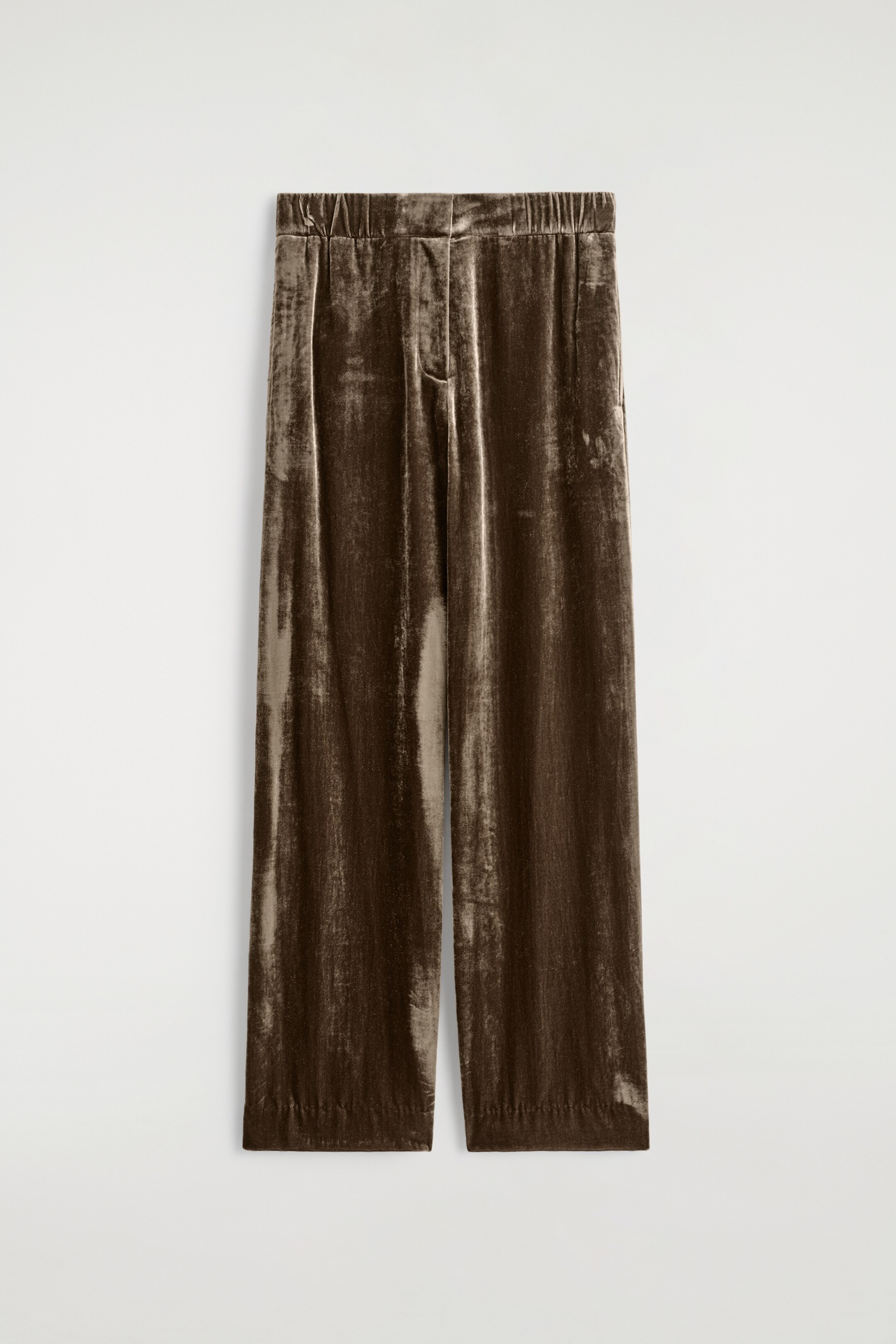 Agrandir l'image: Un pantalon en velours marron foncé est présenté en vue de face. Le pantalon est doté d'une taille élastiquée et de jambes larges, avec le tissu de velours froissé créant une texture scintillante.