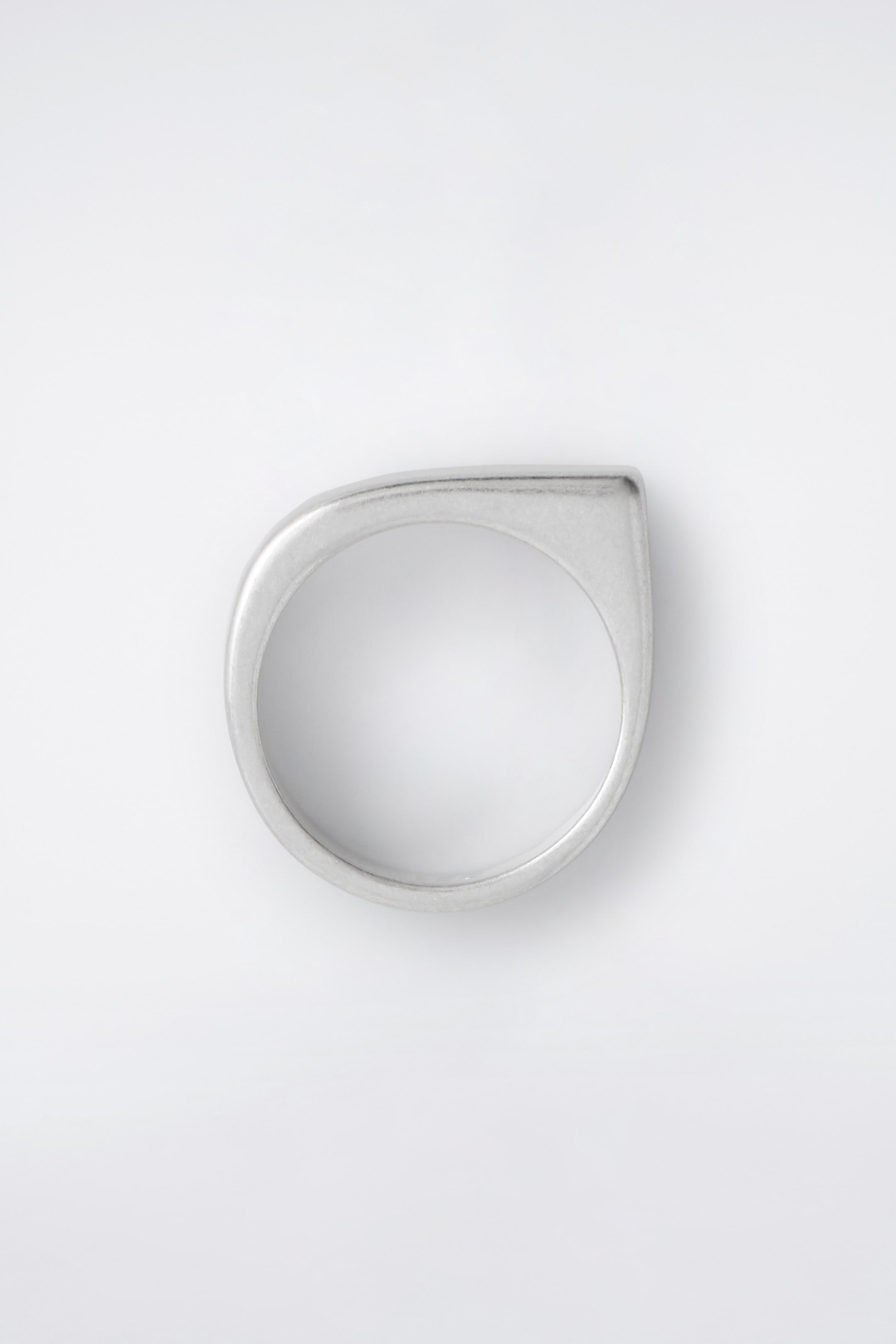 Visualizza immagine più grande: Un anello placcato in argento opaco è presentato FRONTE, mettendo in mostra il suo design scultoreo e asimmetrico. Un lato della fascia è curvato dolcemente, mentre il lato opposto è squadrato.
