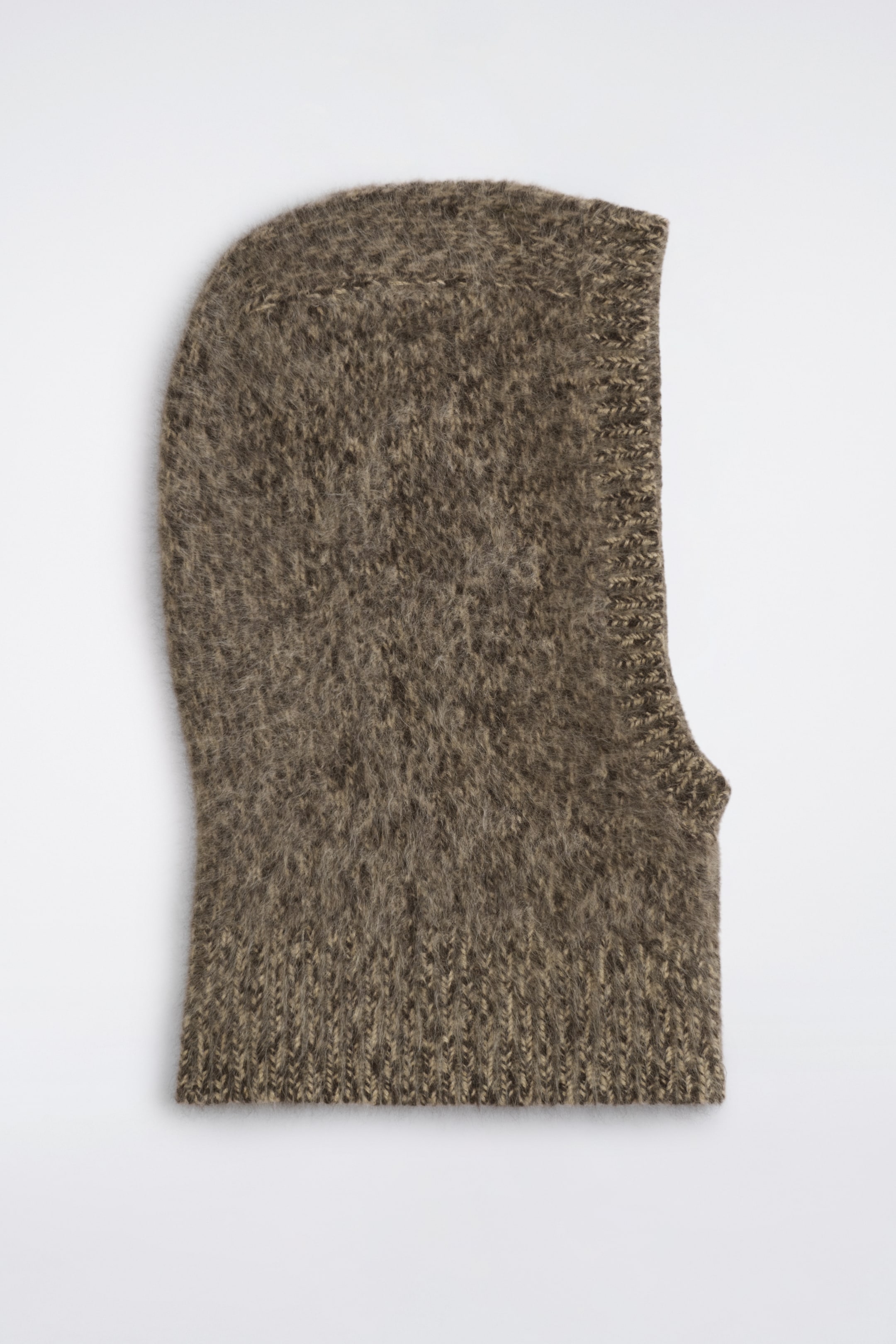 Ver imagen más grande: Una balaclava de cachemira cepillada en punto marrón jaspeado aparece tendida en posición horizontal, vista de perfil lateral, mostrando su superficie suave y texturizada. Presenta un acabado acanalado alrededor de la abertura para el rostro y un amplio bajo acanalado en el cuello.