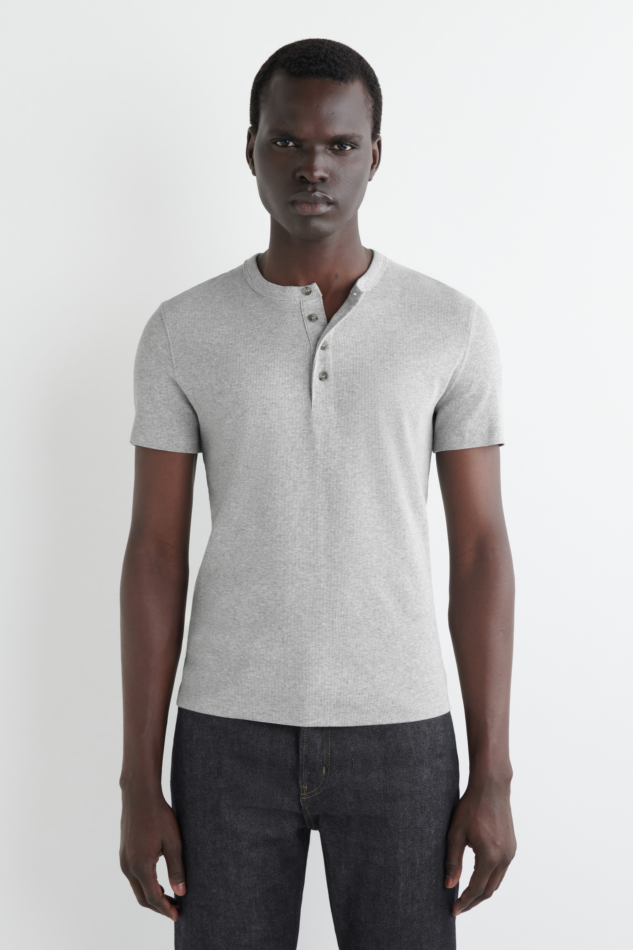 View larger image: A gray short-sleeved henley shirt is featuring a ribbed texture and a round neckline. Its three-button placket is showing one button unfastened, and the shirt is facing front.