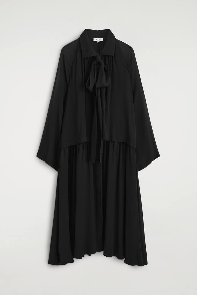 Ein schwarzes Midi-Kleid hÃ¤ngt frontal und verfÃ¼gt Ã¼ber einen spitzen Kragen mit einem integrierten Schal, der am Ausschnitt gebunden ist. Das Design umfasst weit geschnittene, drapierte lange Ãrmel und einen gerafften, flieÃenden Rock. - 1