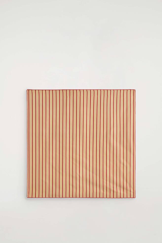 A square striped silk scarf is laid flat in a front view, showcasing its pattern of vertical red and beige stripes. The design features thin black pinstripes between the main stripes and is finished with a solid red stitched border. - 1