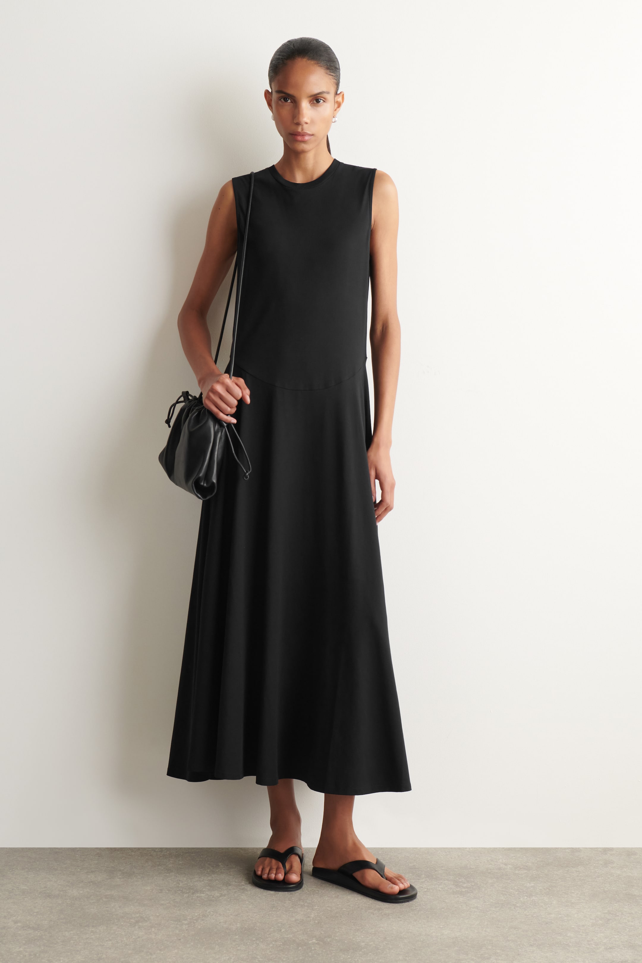 Größeres Bild ansehen: Ein schwarzes ärmelloses Midikleid mit Rundhalsausschnitt, einer horizontalen Naht unterhalb der Taille und einem fließenden A-Linien-Rock.