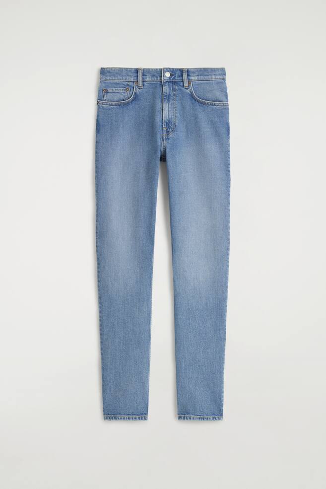 I jeans in denim azzurro chiaro presentano una vista frontale, mostrando una silhouette a gamba stretta con vita alta. Sono dettagliati con una chiusura a bottone e zip, due tasche anteriori e un piccolo taschino per le monete. - 1