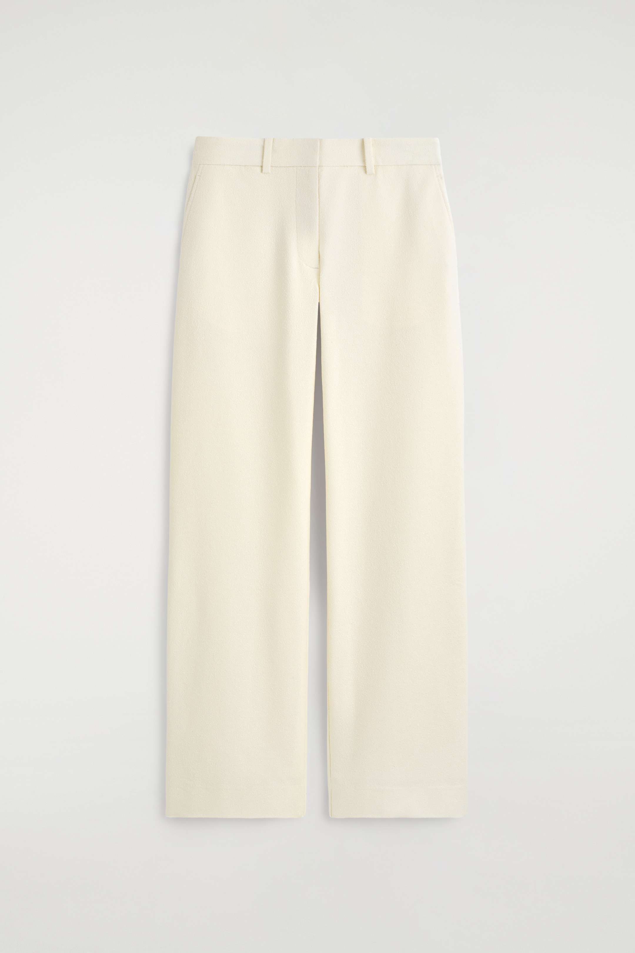 Visualizza immagine più grande: I pantaloni color écru sono mostrati frontalmente, presentano una forma slim a gamba dritta con pieghe pressate che corrono lungo il centro di ciascuna gamba. Sono realizzati in un tessuto Dobby con una texture sottile, tasche laterali, passanti per cintura e chiusura frontale con zip.