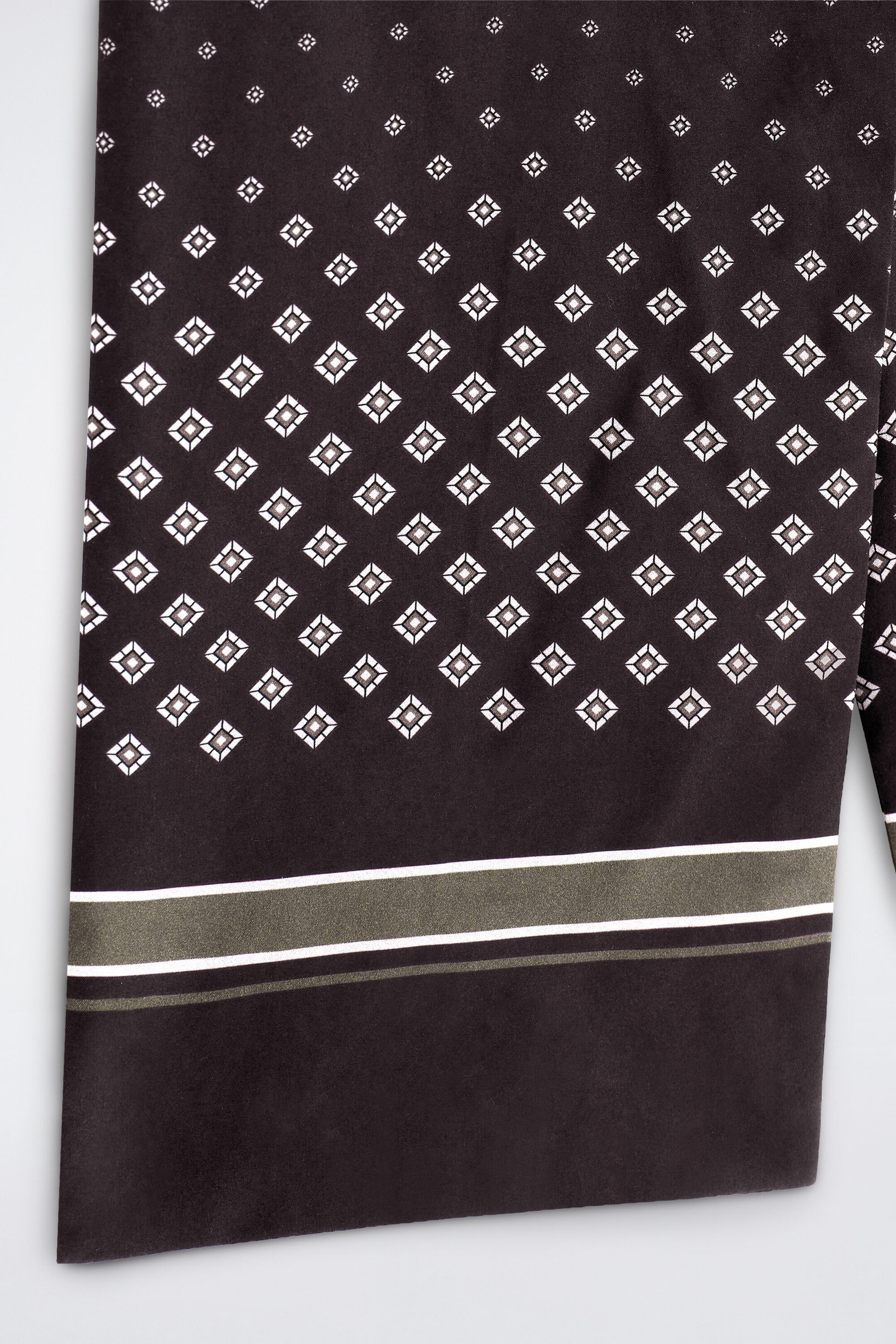 A close-up view of a dark brown silk scarf displaying a geometric pattern of white and grey micro-diamonds. The lower end features horizontal olive-green and white stripes above a solid dark brown border. A close-up view of a dark brown silk scarf displaying a geometric pattern of white and grey micro-diamonds. The lower end features horizontal olive-green and white stripes above a solid dark brown border.