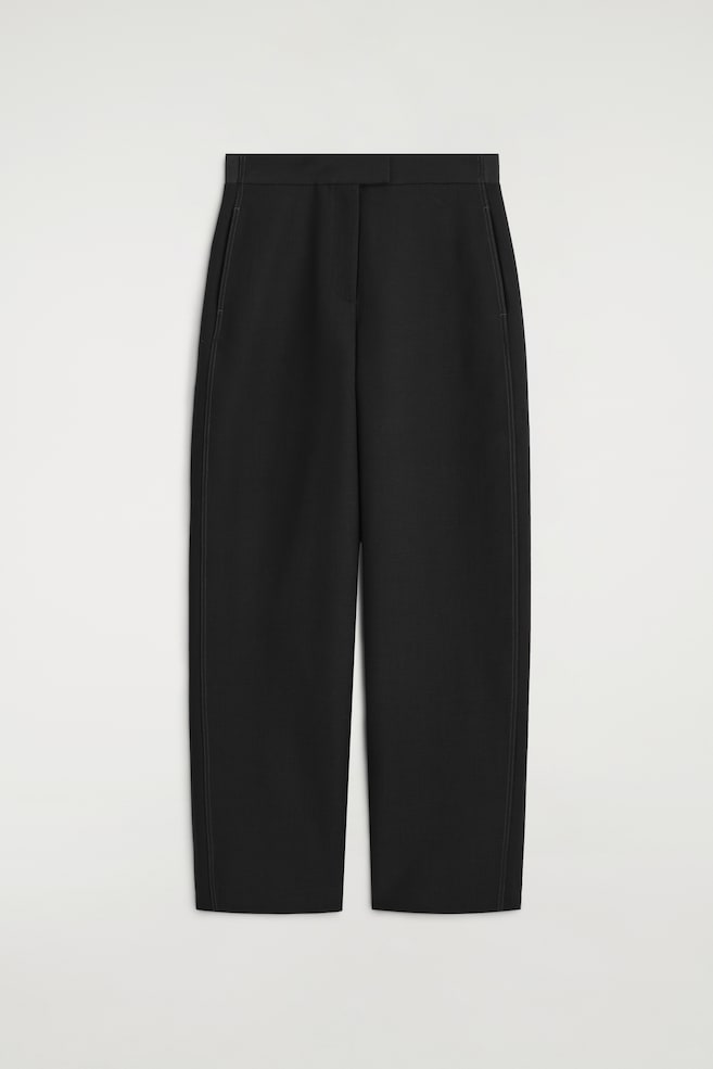 Die Barrel-Leg-Hose mit Steppnähten zeigt in der Frontansicht eine strukturierte, geschwungene Silhouette. Sie verfügt über einen hoch geschnittenen Bund mit verdecktem Verschluss, Seitentaschen und markante vertikale Steppnähte entlang der äuÃeren Nähte. - 1