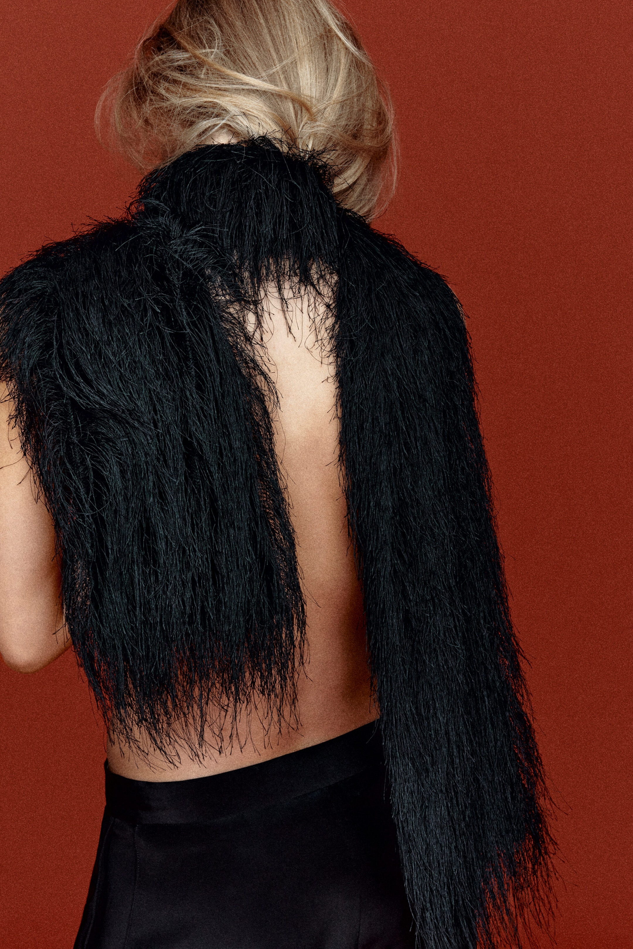 A black scarf featuring dense, wispy fringe is draped over a model’s bare shoulders, shown from the back. The fine, feather-like strands of the fringe cascade downward, creating a highly textured, shaggy look. A black scarf featuring dense, wispy fringe is draped over a model’s bare shoulders, shown from the back. The fine, feather-like strands of the fringe cascade downward, creating a highly textured, shaggy look.