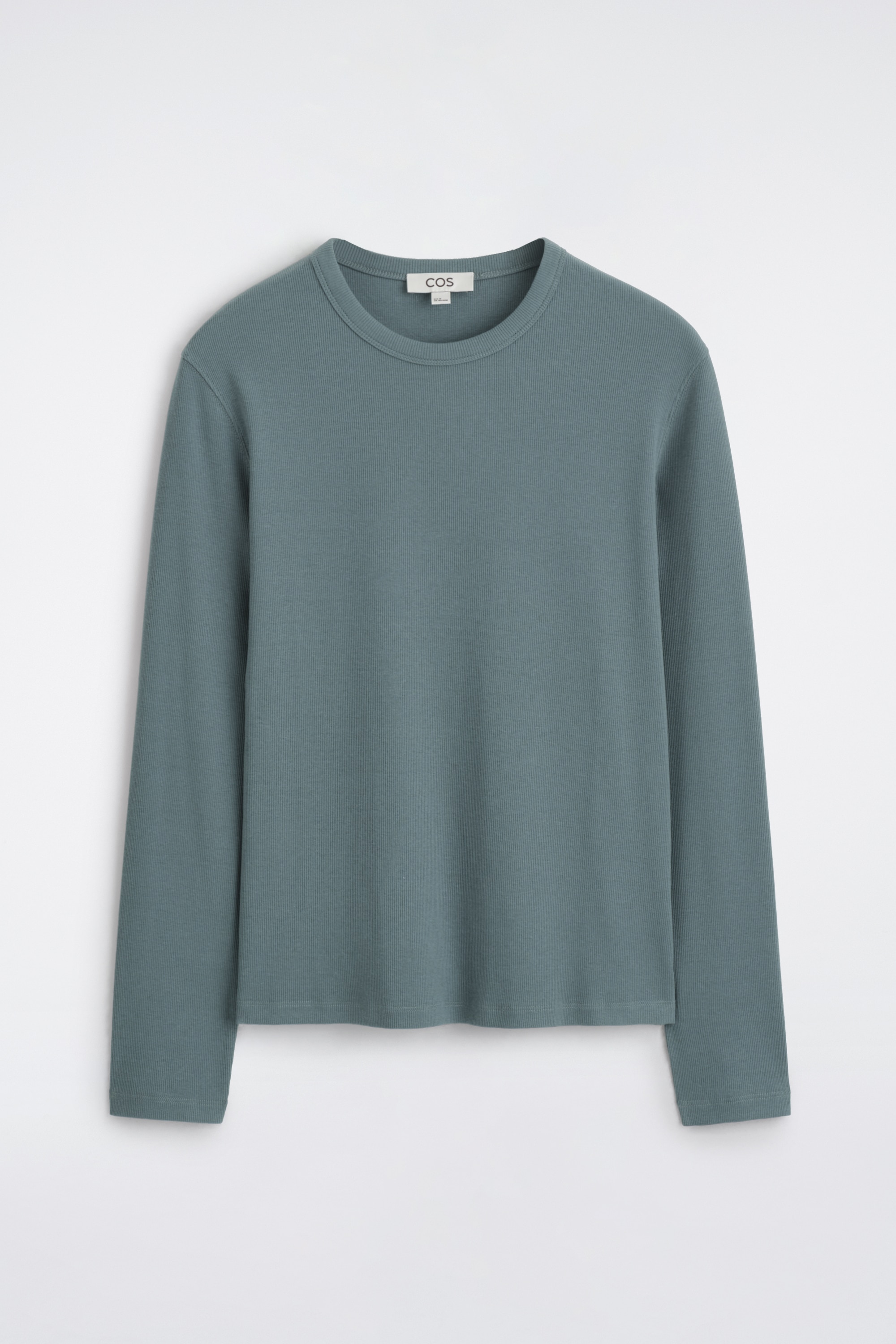 Dit shirt met lange mouwen en ronde hals in een gedempte tealgroene kleur wordt vanuit een frontale hoek gepresenteerd in een slim fit. Het fijngebreide topje is ingestopt in geplooide olijfgroene pantalons met een zwarte leren riem, waardoor de strakke valling en het gestructureerde silhouet extra worden benadrukt.
