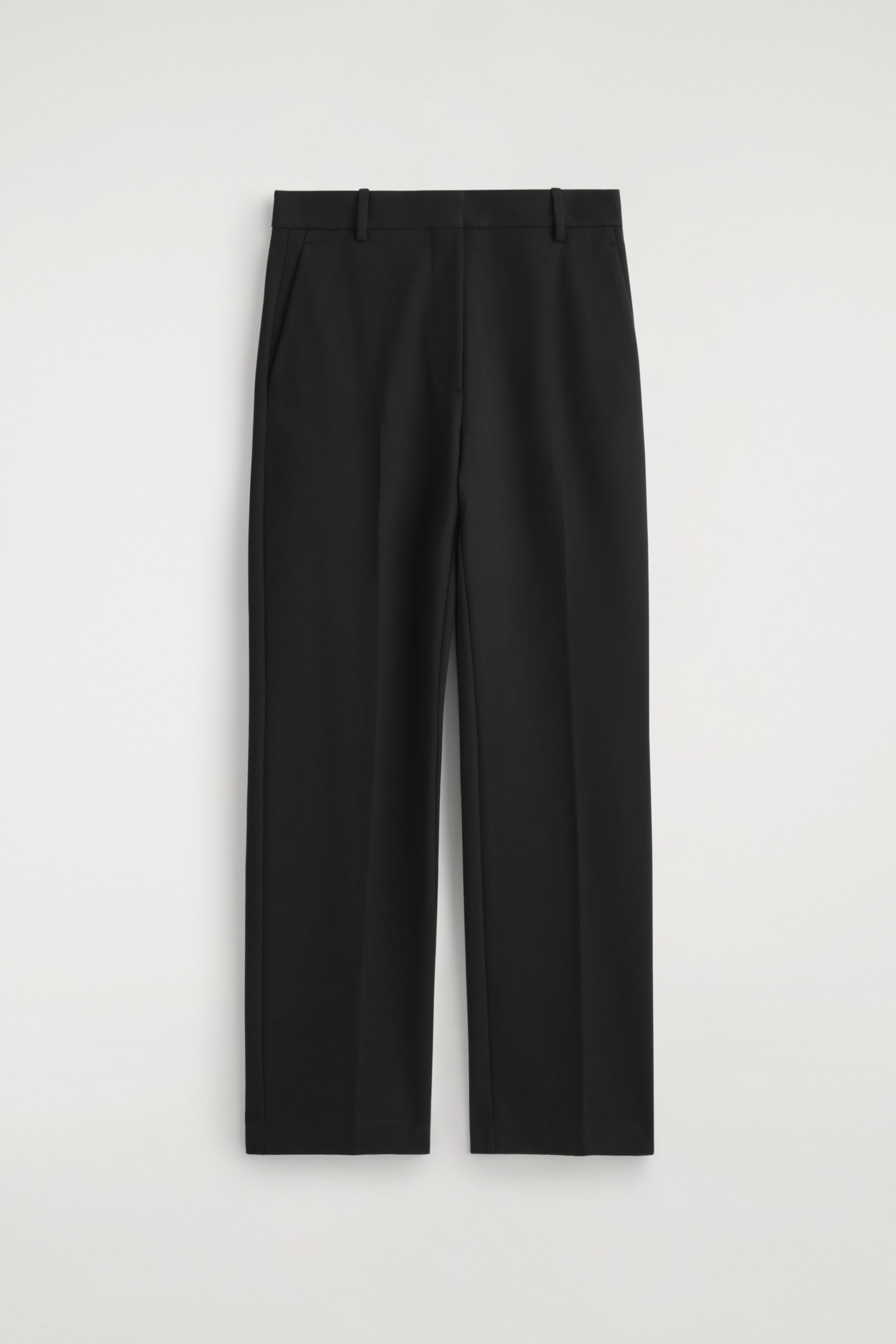 Agrandir l'image: Un pantalon noir est présenté de face, avec une ceinture plate avec des passants, des poches latérales et un pli central descendant chaque jambe droite.