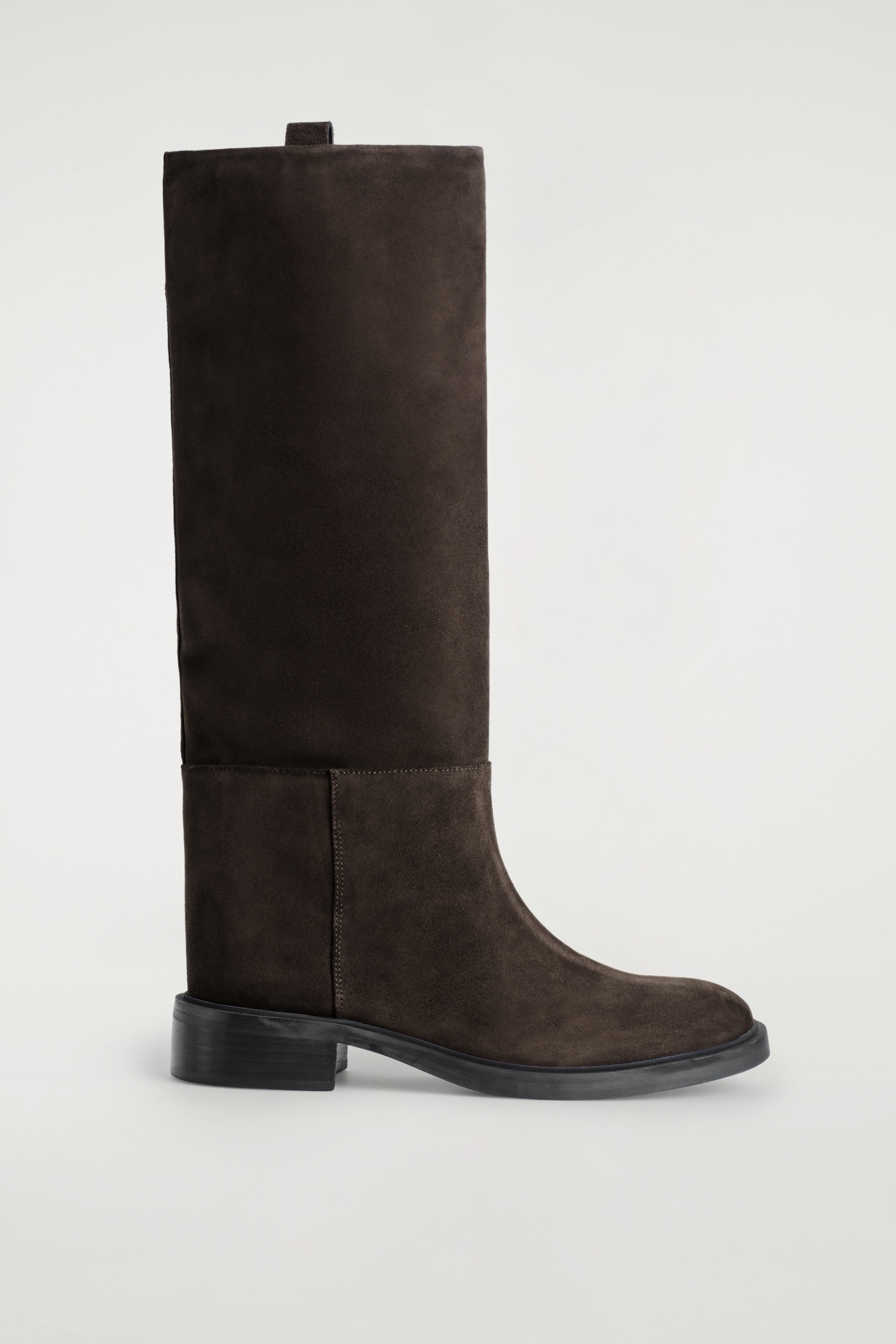 Größeres Bild ansehen: Ein espressofarbenes Wildlederstiefel steht im Seitenprofil, mit einem hohen Schaft, einer abgerundeten Zehe und einem niedrigen Blockabsatz mit dunkler Sohle. Eine horizontale Naht ist über den unteren Schaft sichtbar, und eine kleine Zuglasche befindet sich oben.