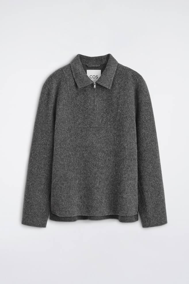 Een donkergrijze, getextureerde gebreide pullover is van voren afgebeeld, met een spreadkraag en een half-zip-sluiting met een zilverkleurige ritstrekker. Het kledingstuk met lange mouwen heeft een zachte, geborstelde afwerking, een relaxte pasvorm en een rechte zoom. - 1