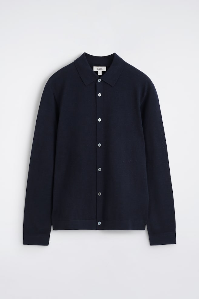 A navy blue fine-knit collared shirt is facing forwards, featuring a point collar, a full-button placket with seven light-coloured buttons, and long sleeves with ribbed cuffs and hem. - 1