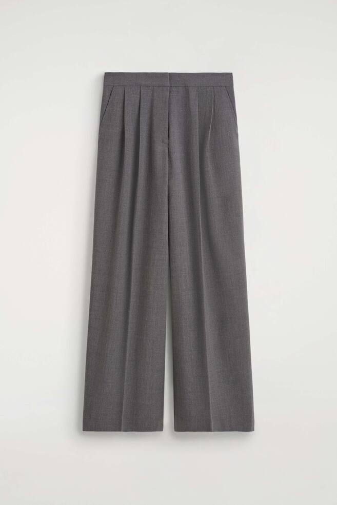 Grijze broek met plooien en wijde pijpen, van voren afgebeeld, met een hoge taille en dubbele plooien aan beide zijden. De broek heeft een silhouet met wijde pijpen, met geperste vouwen in het midden van elk broekspijp en subtiele steekzakken aan de zijkant. - 1