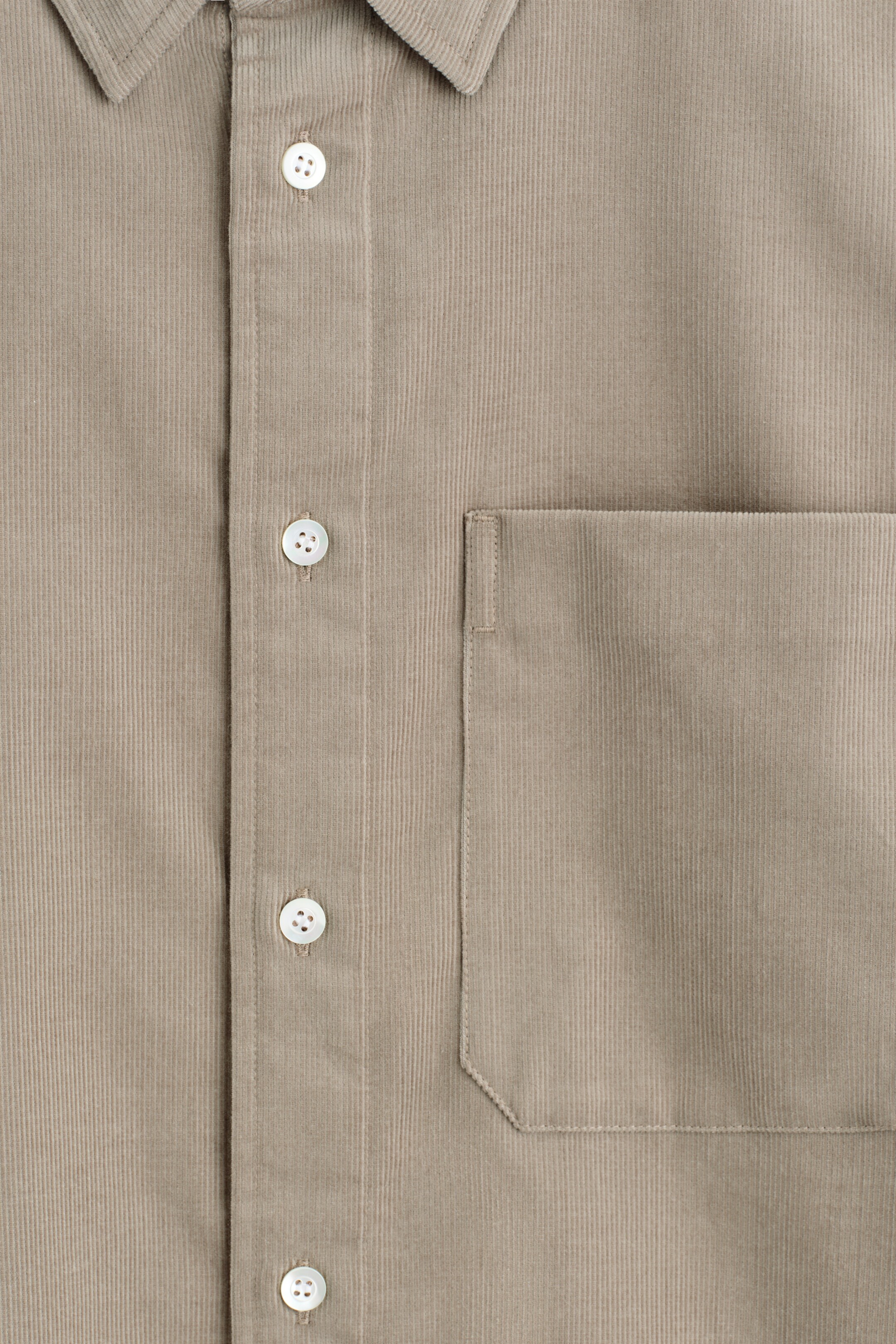 View larger image: The FRONT of a light brown corduroy shirt is displaying its distinct vertical ribbed texture. It is featuring a central button placket with white mother-of-pearl buttons and a single patch chest pocket on the left side.