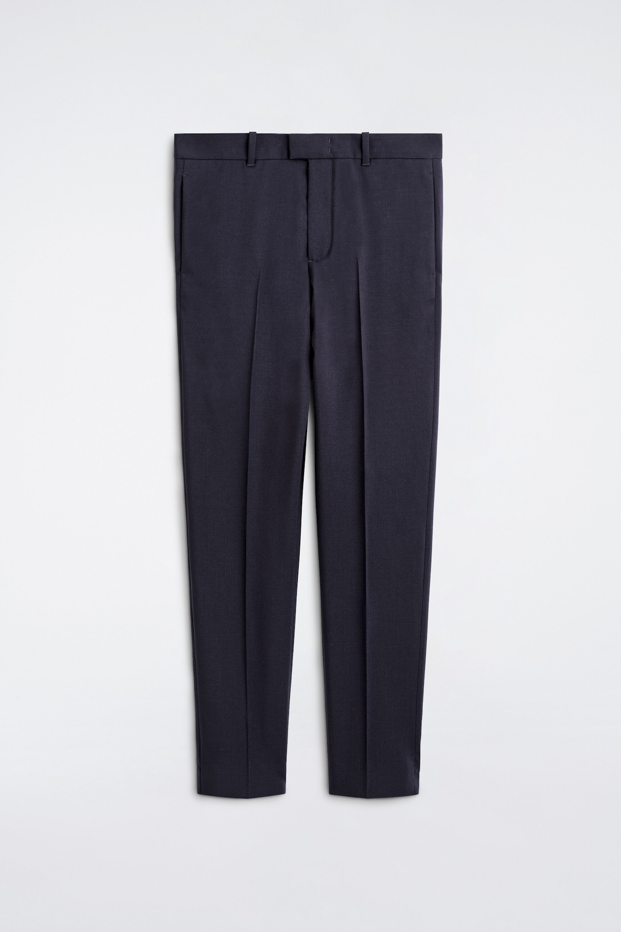 Le pantalon droit slim en laine est présenté de face, dans une teinte bleu marine foncé, avec une ceinture structurée munie de passants et une fermeture frontale dissimulée. Le pantalon affiche des plis marqués au fer courant le long du centre de chaque jambe, ainsi que de discrètes poches latérales en biais.