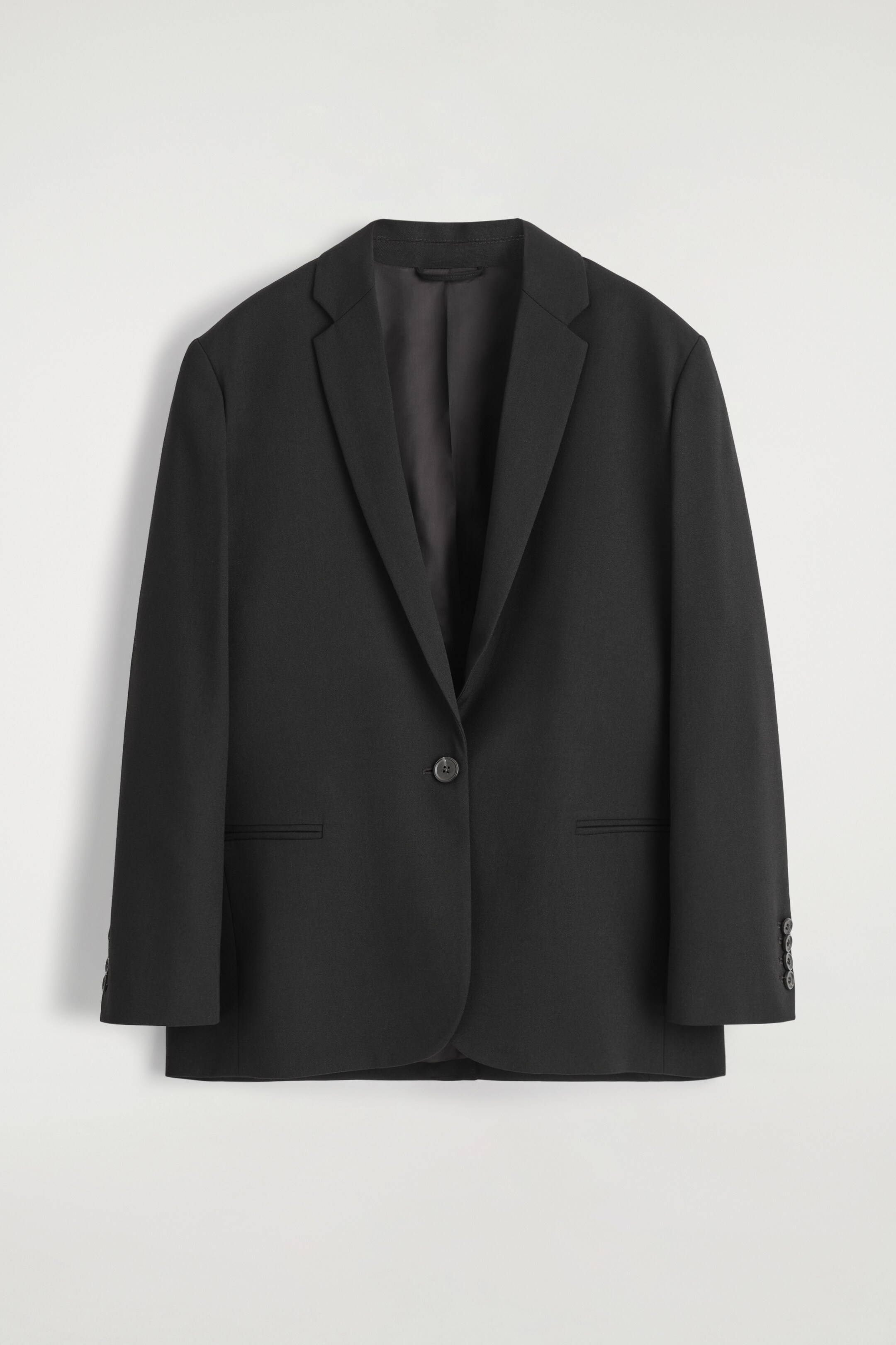 Größeres Bild anzeigen: Ein schwarzer einreihiger Blazer wird VON VORNE gezeigt, mit breiten Kerbrevers, einem Ein-Knopf-Verschluss und zwei horizontalen Leistentaschen. Der Blazer hat eine normale Passform und geknöpfte Manschetten an beiden Ärmeln.