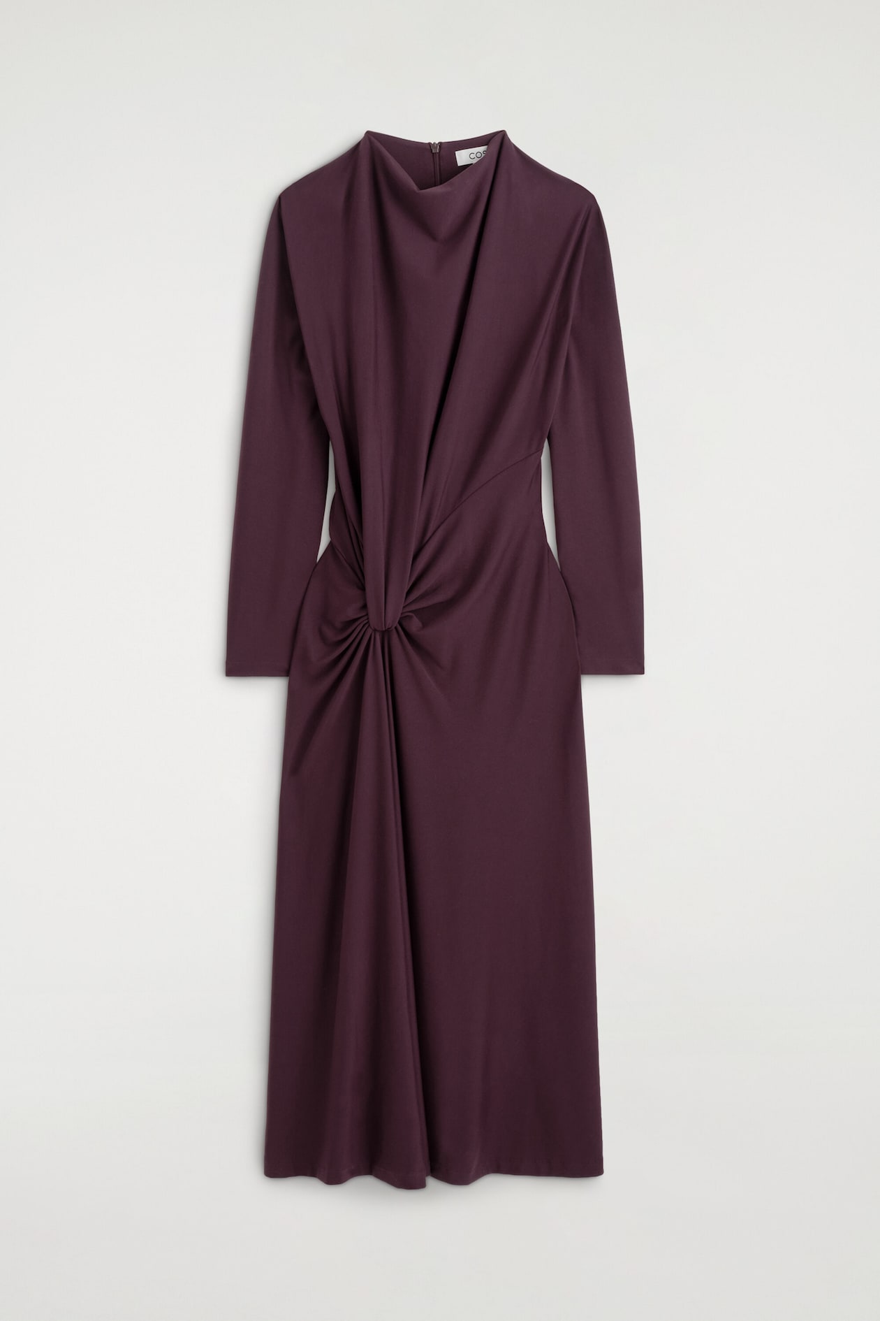 La robe midi à détail torsadé et drapé est présentée de face dans une teinte prune foncée, avec un col bénitier drapé montant et des manches longues. Un détail torsadé central à la taille crée des plis froncés qui retombent sur le corsage et la jupe longueur midi.