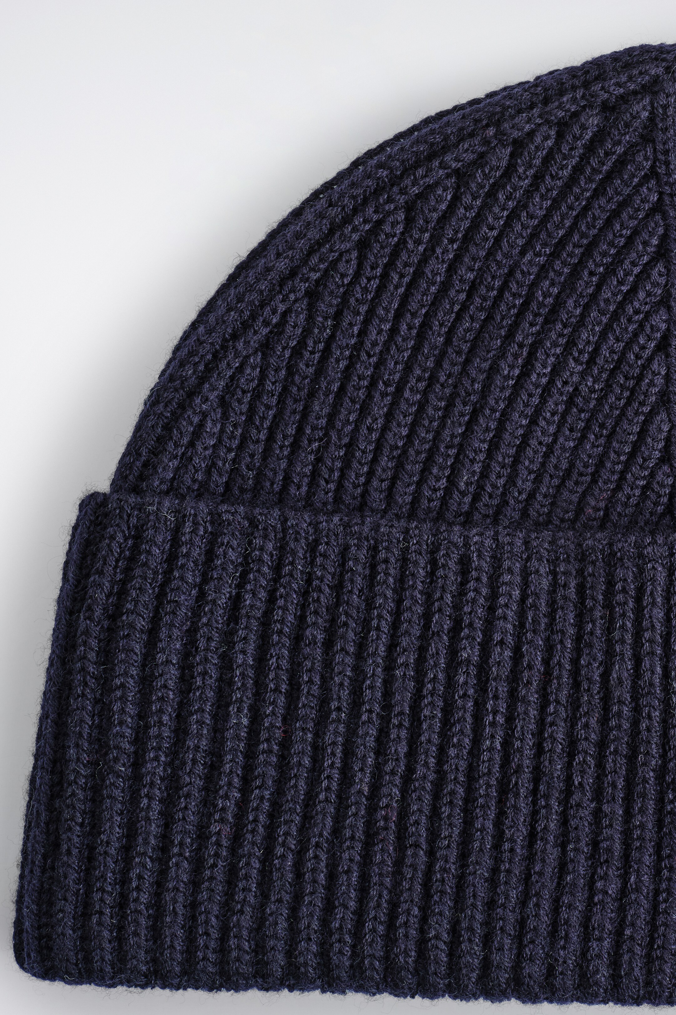Agrandir l'image: Un bonnet en tricot marine est présenté, avec une construction en tricot côtelé et un large bord replié.