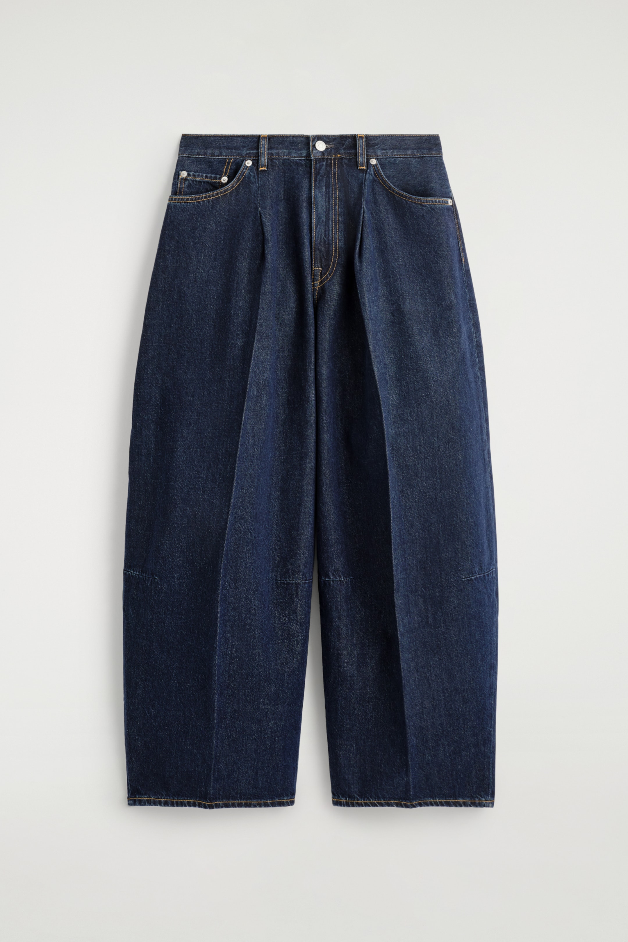 Visualizza immagine più grande: Un paio di jeans a gamba larga blu scuro è mostrato dal davanti, con pieghe piegate prominenti che corrono lungo la parte anteriore di ciascuna gamba. Questi jeans a vita media includono una chiusura con bottone e zip, tasche frontali oblique con un taschino per le monete e dettagli di cuciture orizzontali sulle gambe inferiori, tutti accentuati con cuciture a contrasto.