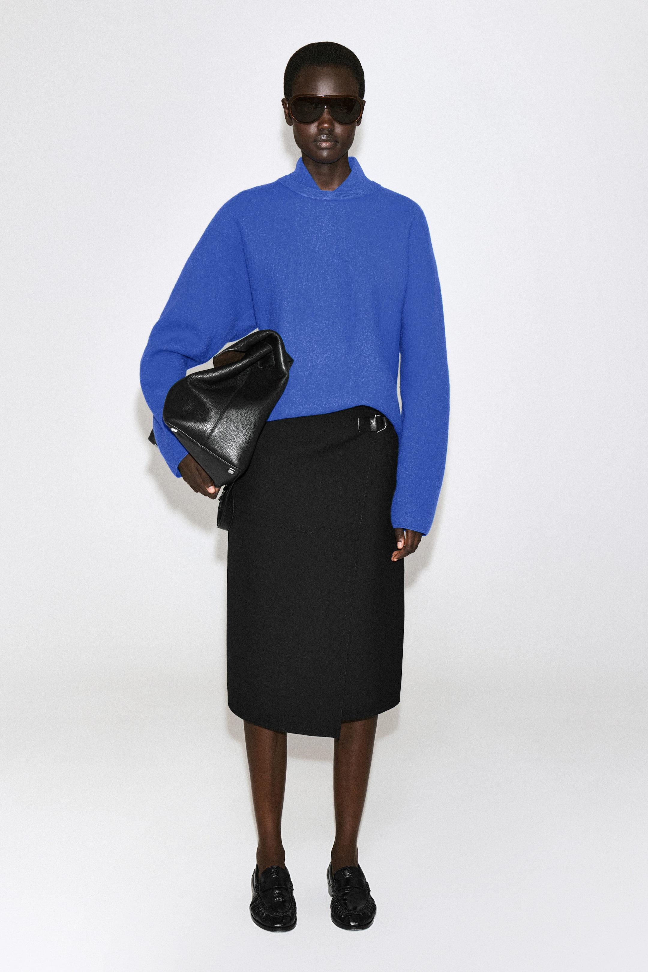 Le pull en laine bouillie à col superposé est présenté de face, dans une couleur bleu cobalt vibrante, avec un col haut superposé et une silhouette décontractée à manches longues. Le pull en laine texturée est porté partiellement rentré dans une jupe portefeuille noire longueur genou. Le pull en laine bouillie à col superposé est présenté de face, dans une couleur bleu cobalt vibrante, avec un col haut superposé et une silhouette décontractée à manches longues. Le pull en laine texturée est porté partiellement rentré dans une jupe portefeuille noire longueur genou.