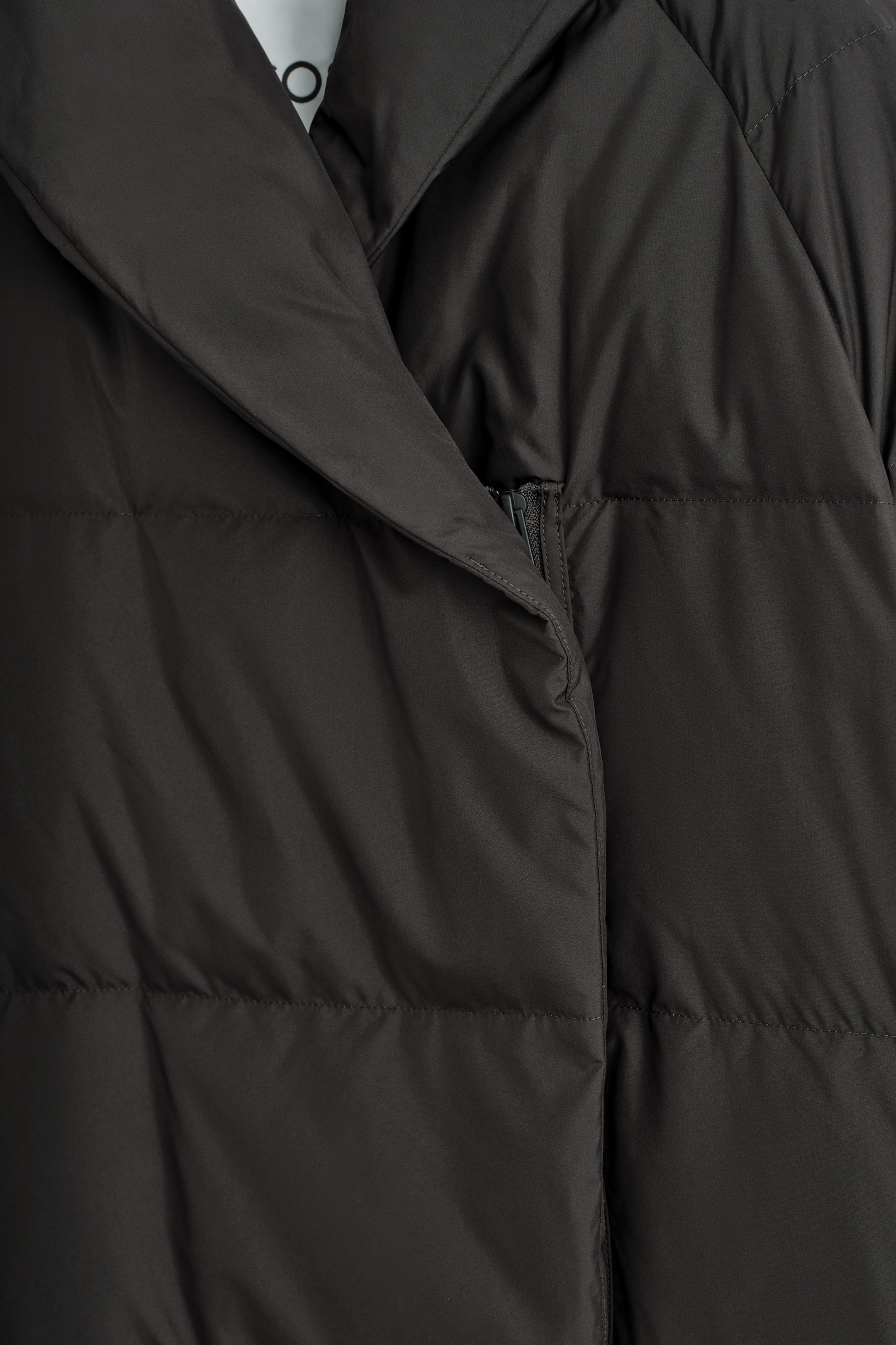 View larger image: A dark grey puffer coat is featuring a prominent shawl collar, a partially concealed front zipper closure, and a quilted design, creating an insulated appearance.