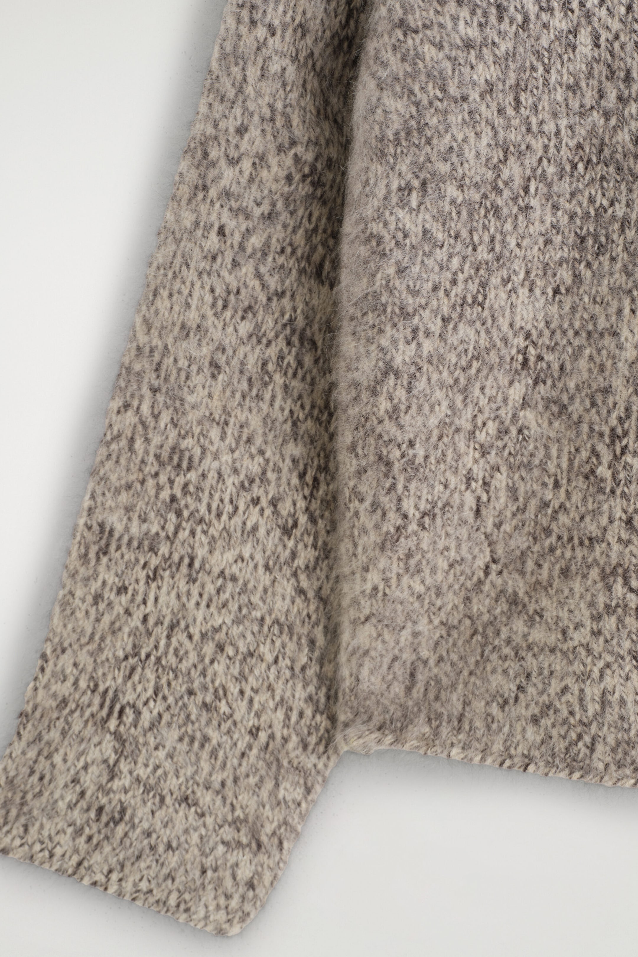 The chunky brushed-cashmere hoodie is showcasing its thick, fuzzy texture in a marled beige and grey knit. The close-up view is highlighting the soft, brushed-knit fibres of the sleeve and body. The chunky brushed-cashmere hoodie is showcasing its thick, fuzzy texture in a marled beige and grey knit. The close-up view is highlighting the soft, brushed-knit fibres of the sleeve and body.