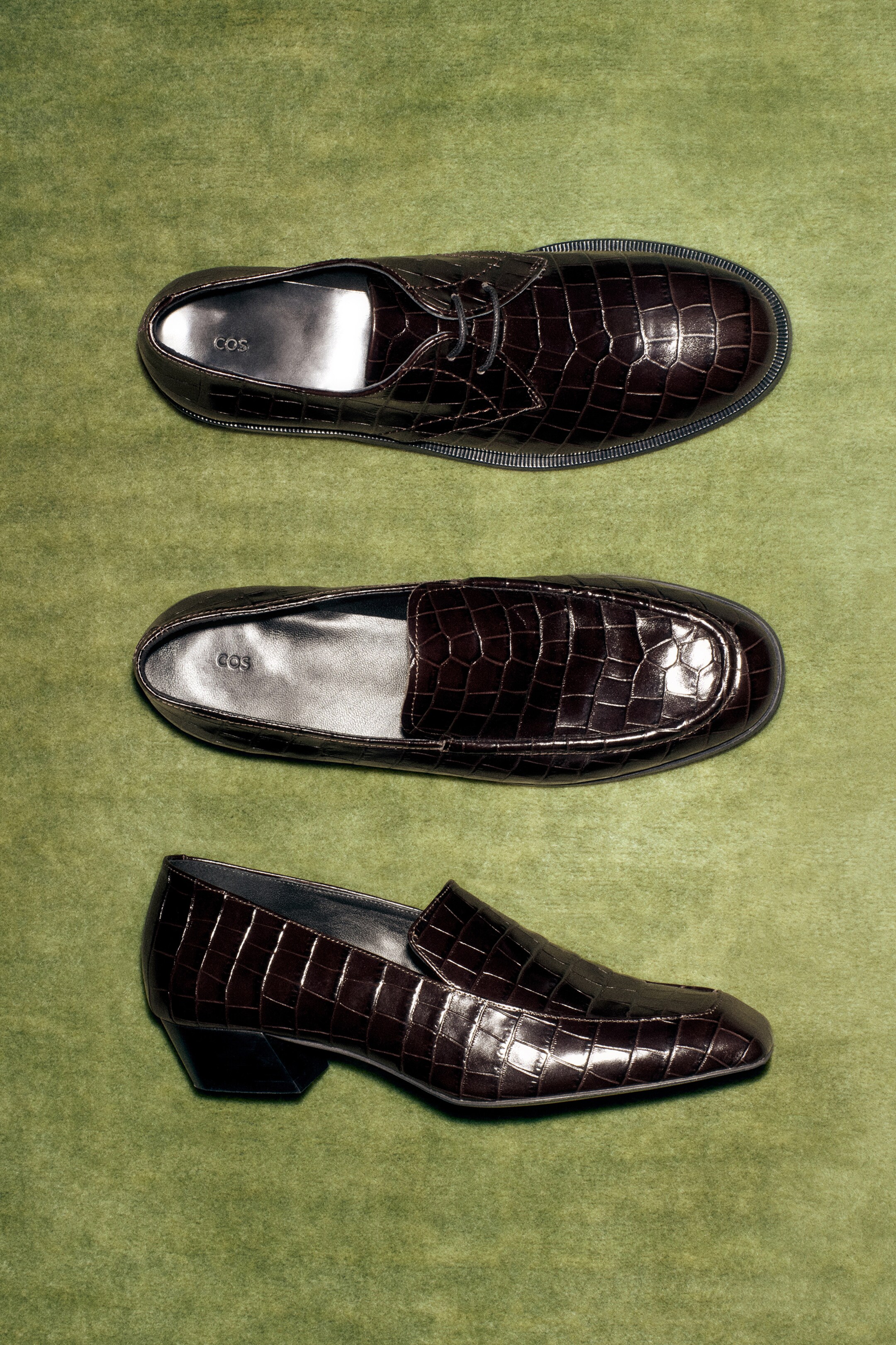 Größeres Bild anzeigen: Drei Paar espresso-braune Schuhe werden ausgestellt: ein Schnür-Derby-Schuh und ein Slipper aus der Vogelperspektive sowie ein Loafer mit Absatz aus der Seitenansicht. Alle sind aus poliertem Leder mit Krokodileffekt gefertigt und ruhen auf Gummisohlen.