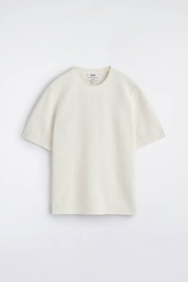 An off-white T-shirt is displayed from the FRONT, highlighting its micro waffle knit texture. It boasts a ribbed crew neck, short sleeves with ribbed cuffs, and a ribbed hem. - 1