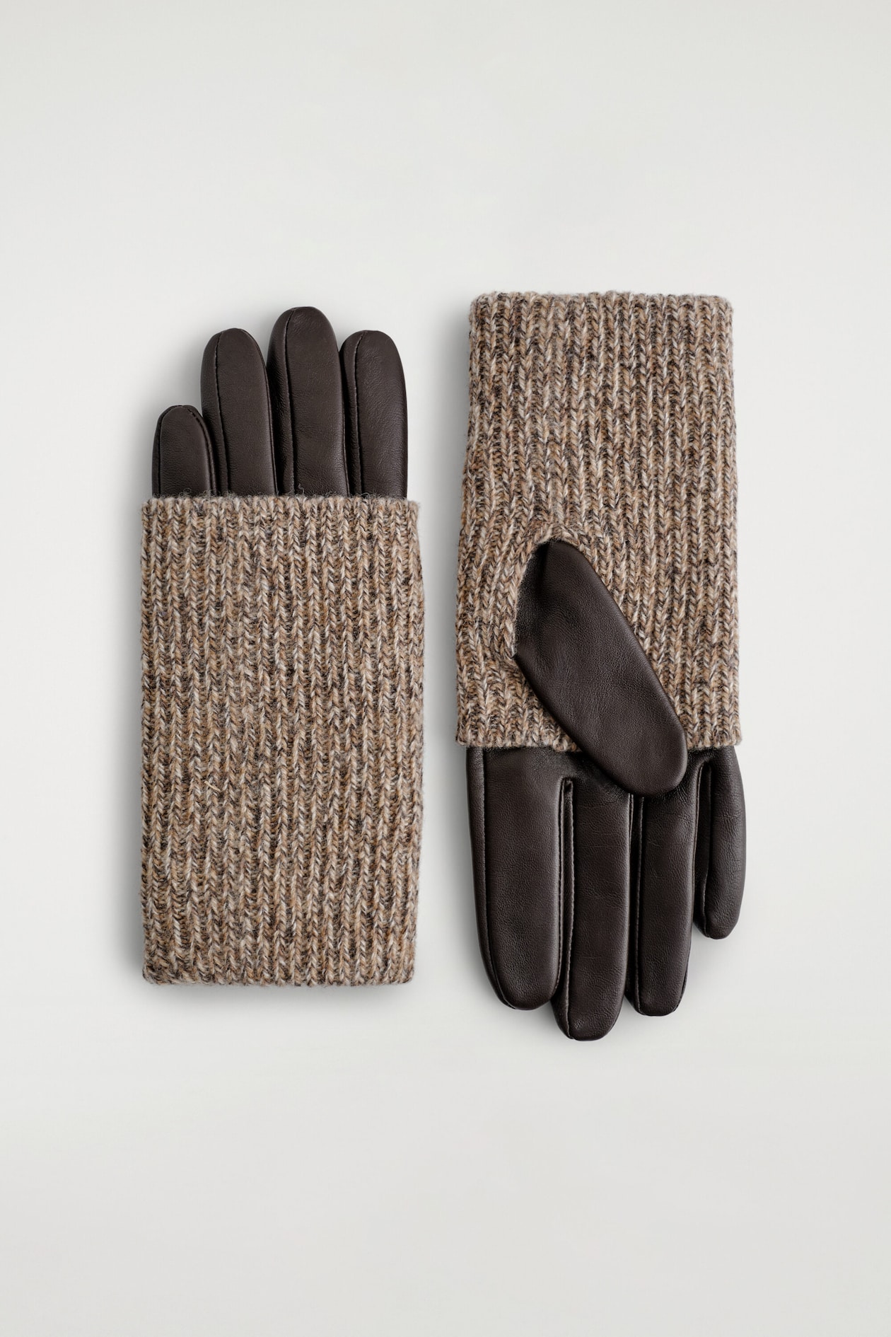 A pair of hybrid gloves combines dark brown leather with a textured beige and brown marled ribbed knit. The glove on the left shows the back-of-hand view with the knit cover layered over the leather fingers, while the glove on the right shows the palm-side view with the leather thumb and fingers exposed.