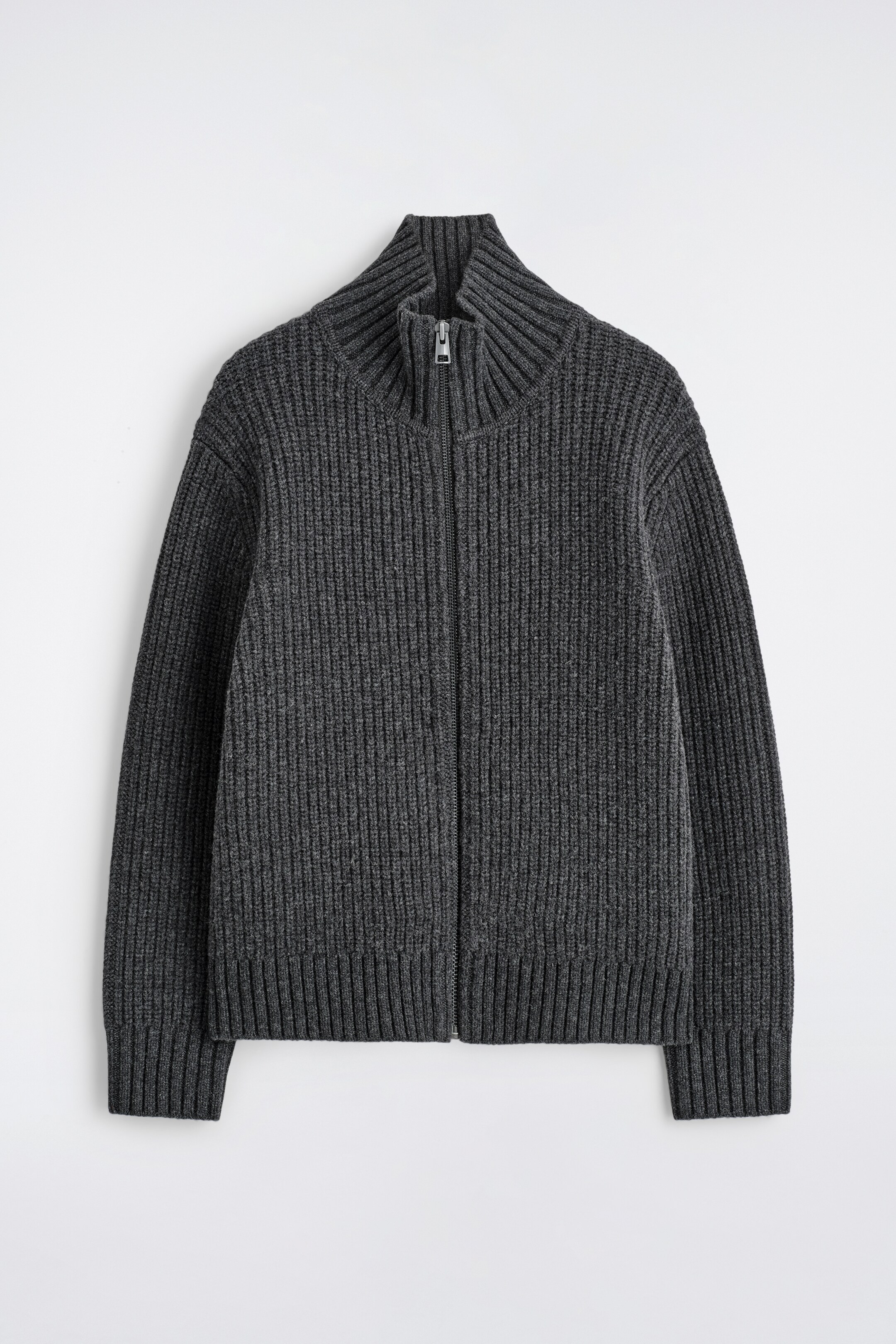 Agrandir l'image: Une veste en tricot gris foncé affiche une texture côtelée sur toute sa surface, face AVANT. Une fermeture éclair de couleur argentée s'étend de l'ourlet jusqu'à son col cheminée côtelé, et des manches longues avec des poignets côtelés et un ourlet côtelé complètent le design.