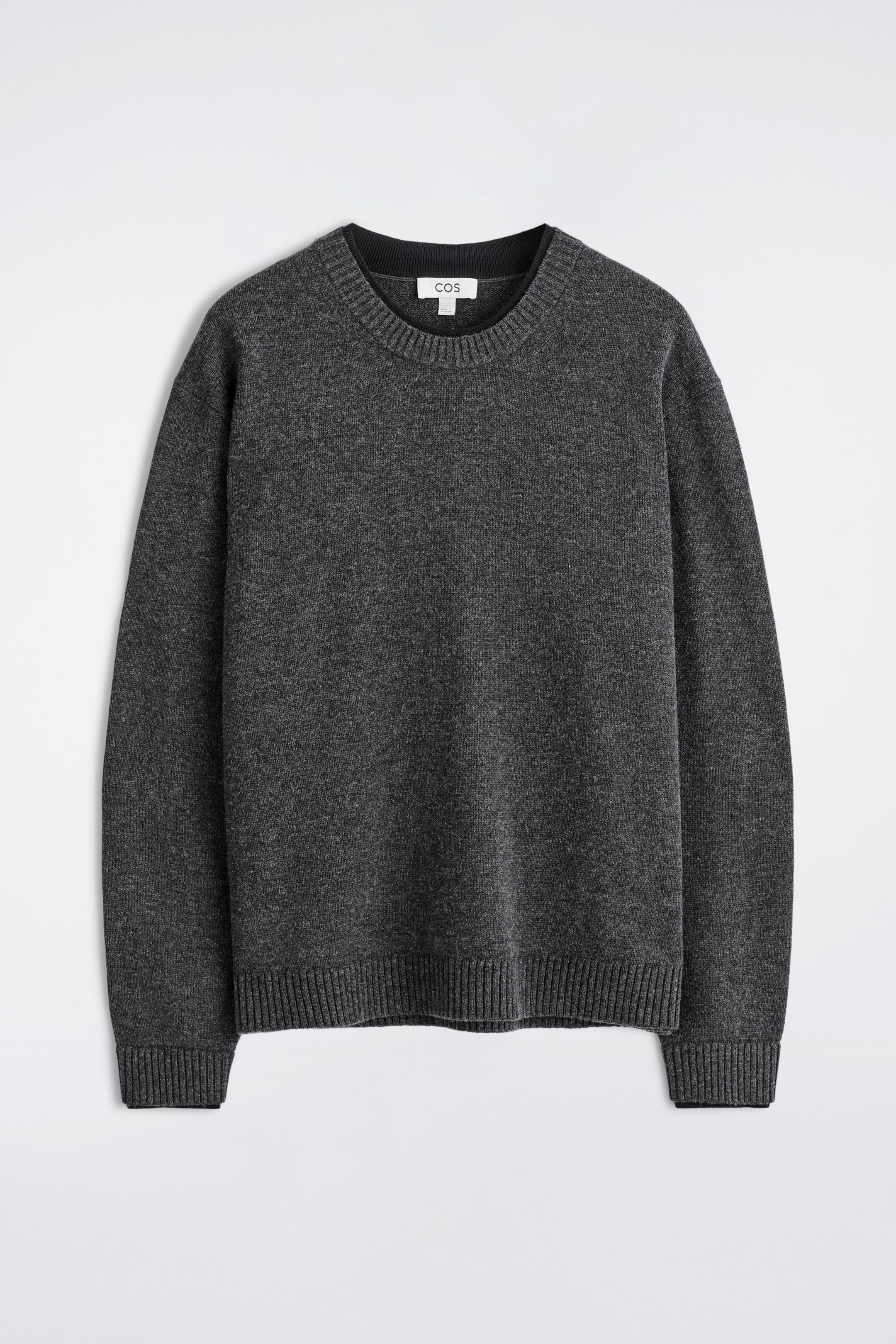 Grösseres Bild ansehen: Ein anthrazitgrauer Merinowollpullover mit Rundhalsausschnitt wird in einer Vorderansicht präsentiert. Er verfügt über einen gerippten Rundhalsausschnitt, gerippte Bündchen und einen gerippten Saum, wobei der Ausschnitt und die Bündchen eine subtile dunkle, doppelt gesäumte Verarbeitung aufweisen.