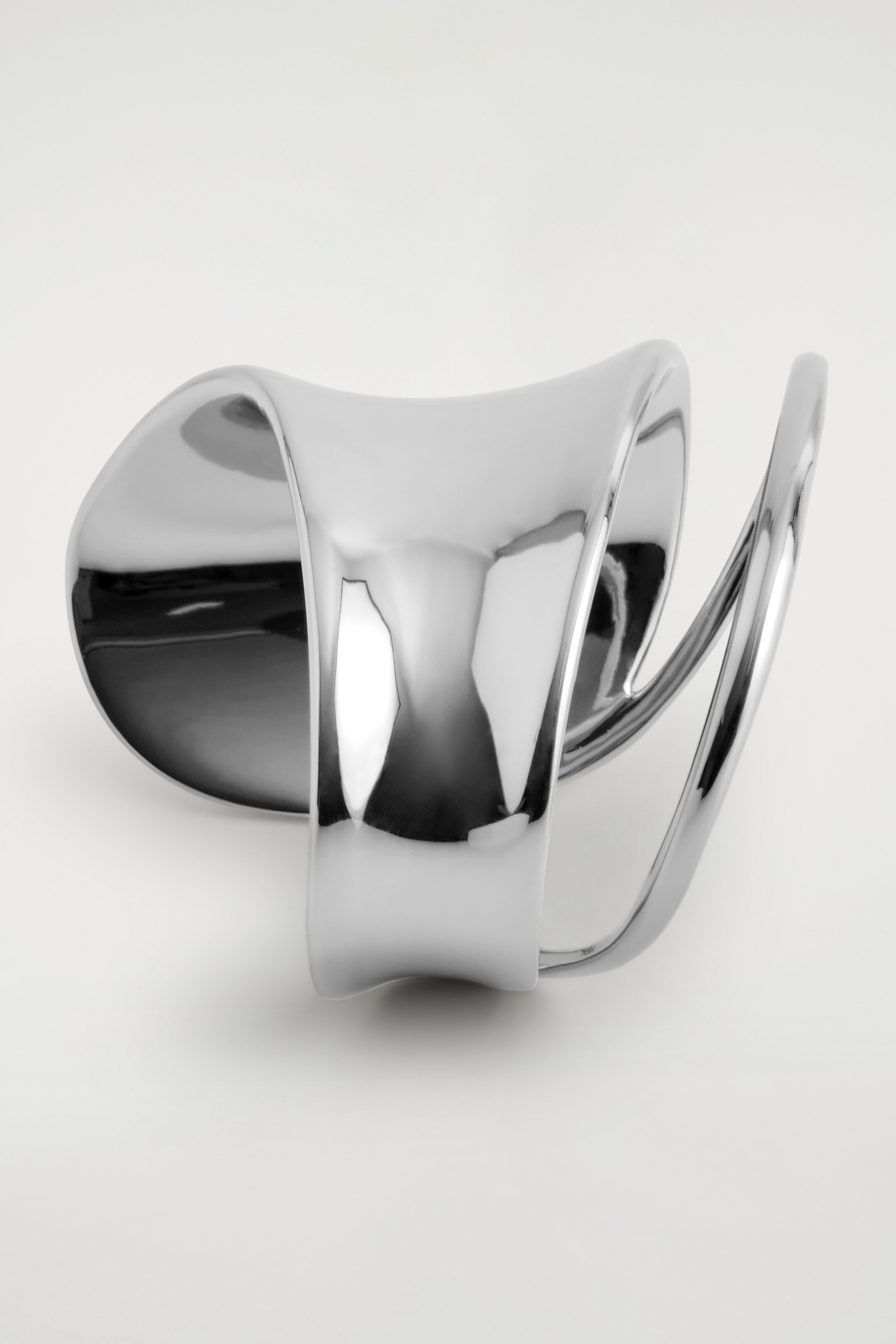 View larger image: A DOUBLE-WRAP CUFF is resting on its bottom, presenting its polished, silver-toned surface. Its wide, smooth band is curving and twisting upwards, seamlessly transitioning into two thinner, parallel bands that are forming an open, sculptural design.