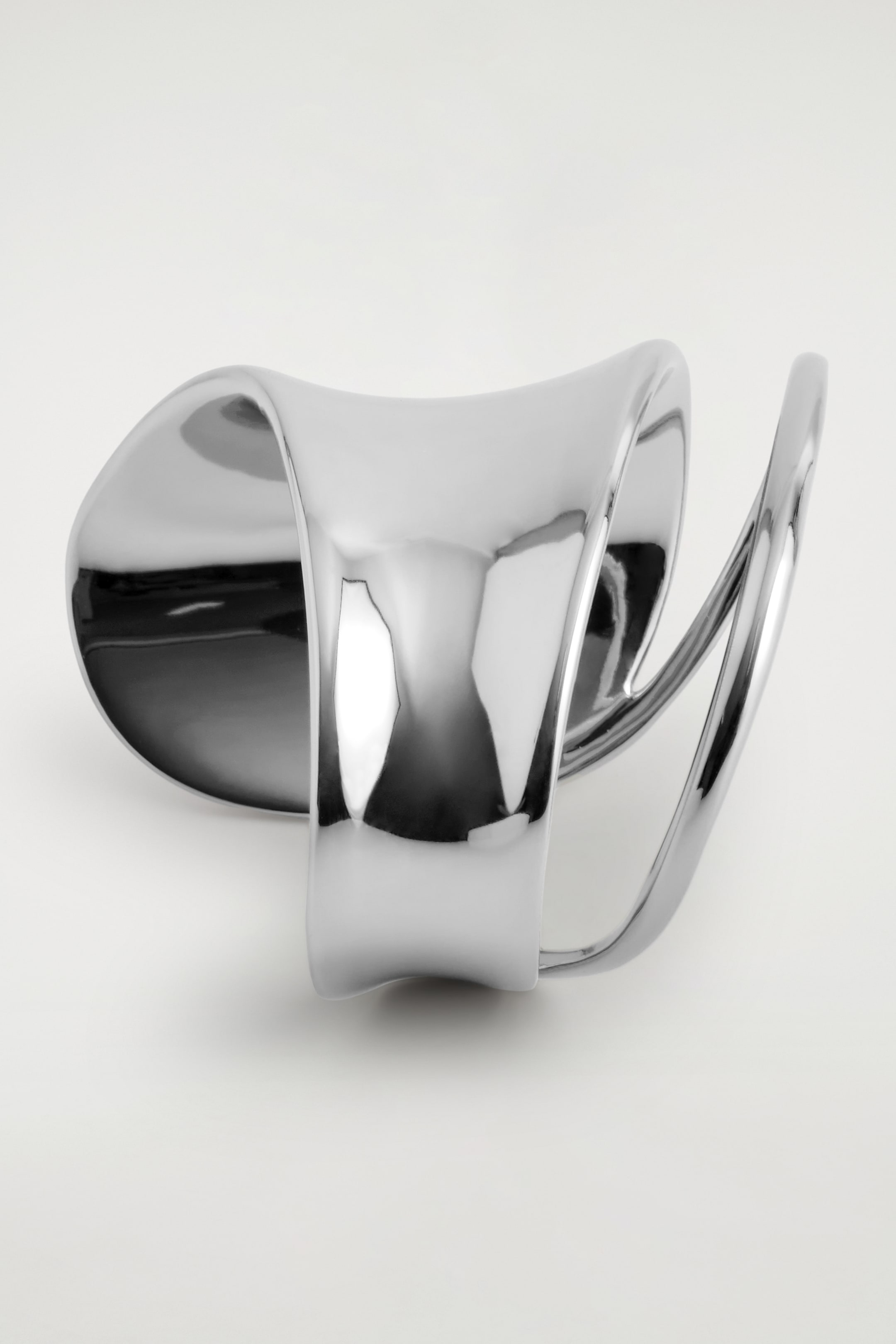 View larger image: A DOUBLE-WRAP CUFF is resting on its bottom, presenting its polished, silver-toned surface. Its wide, smooth band is curving and twisting upwards, seamlessly transitioning into two thinner, parallel bands that are forming an open, sculptural design.
