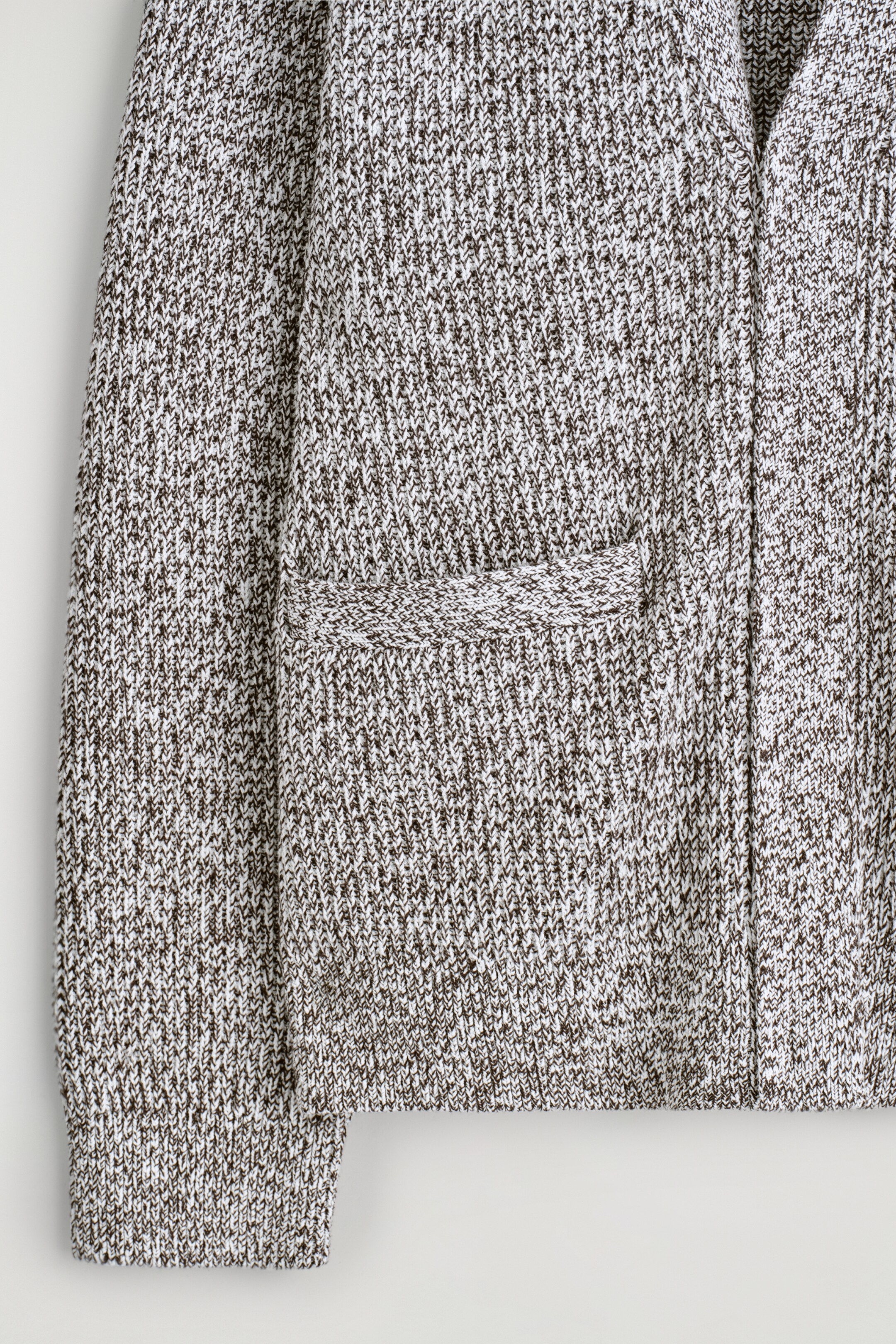 Agrandir l'image: Un cardigan est présenté de FACE, avec un tricot mélangé de fils blancs et foncés, une poche passepoilée visible sur le côté gauche, un poignet côtelé sur la manche et un ourlet côtelé le long du bas.