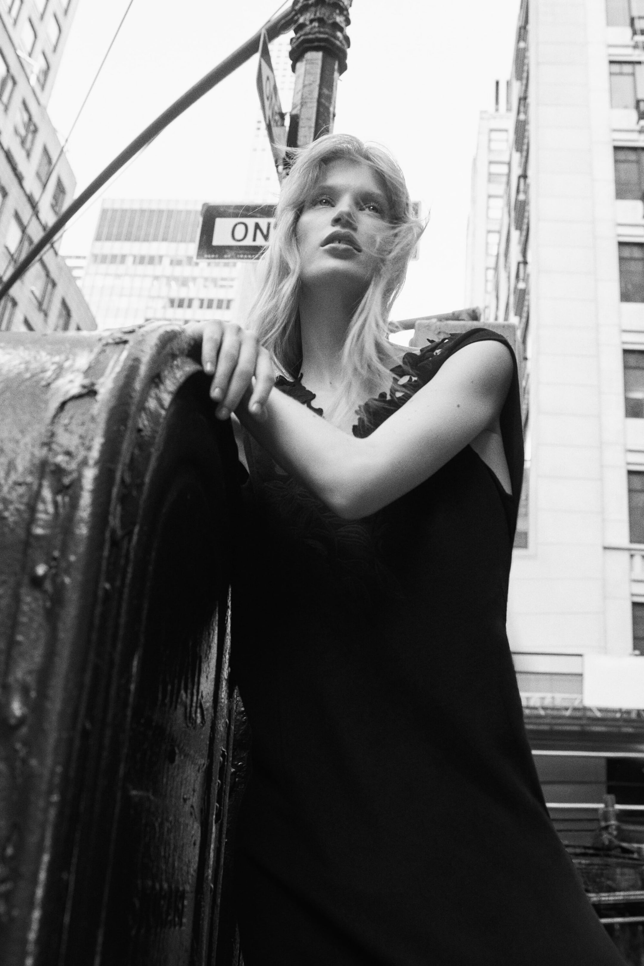 A black sleeveless dress shown from the front features a V-neckline embellished with textured ruffles. The dress drapes softly, showcasing its relaxed fit and fluid silhouette. A black sleeveless dress shown from the front features a V-neckline embellished with textured ruffles. The dress drapes softly, showcasing its relaxed fit and fluid silhouette.