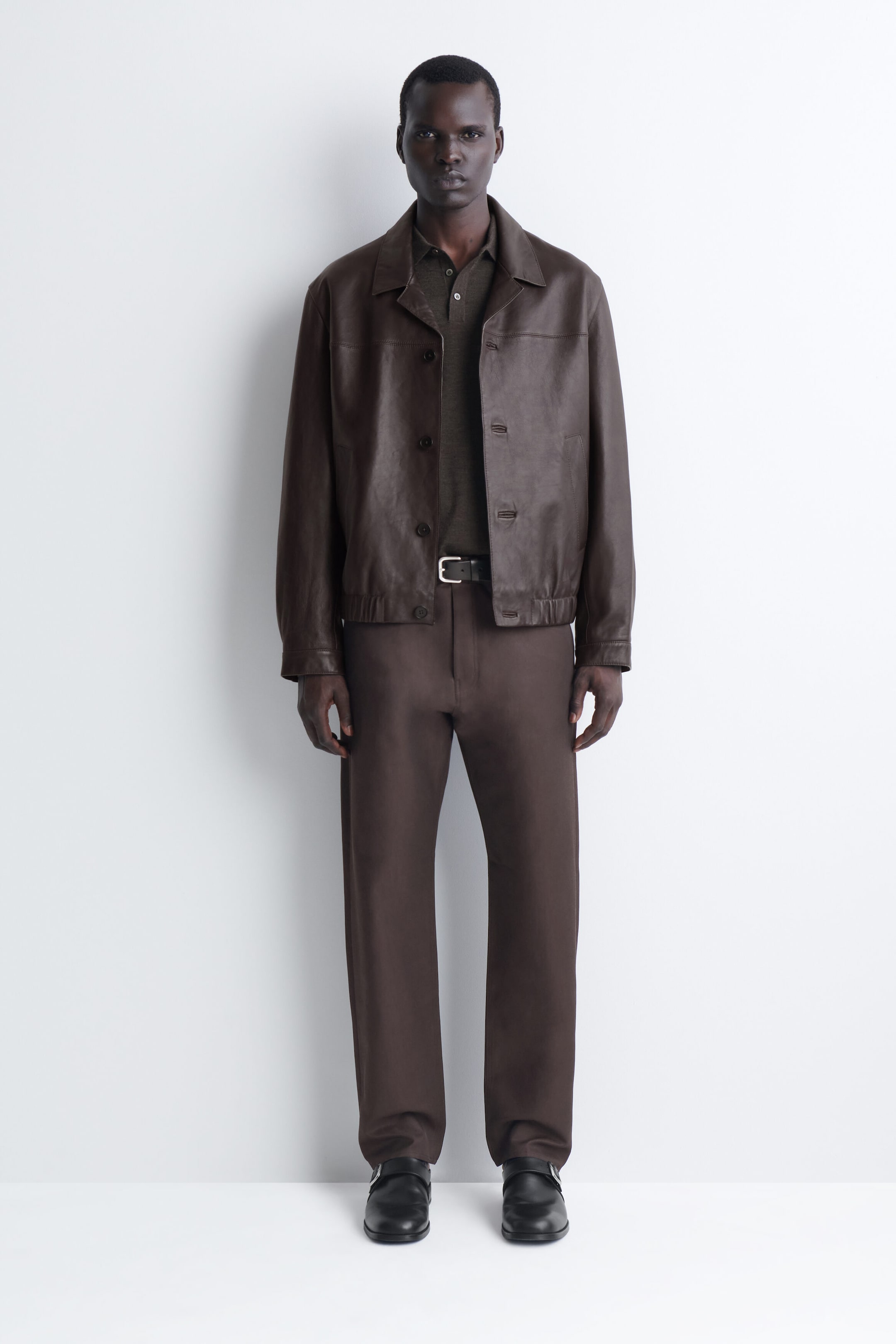 The signature regular-fit straight-leg jeans in dark brown are shown from the front, showcasing their structured, straight-cut silhouette. The jeans feature a clean waistband styled with a belt and fall straight to rest over black leather shoes. The signature regular-fit straight-leg jeans in dark brown are shown from the front, showcasing their structured, straight-cut silhouette. The jeans feature a clean waistband styled with a belt and fall straight to rest over black leather shoes.