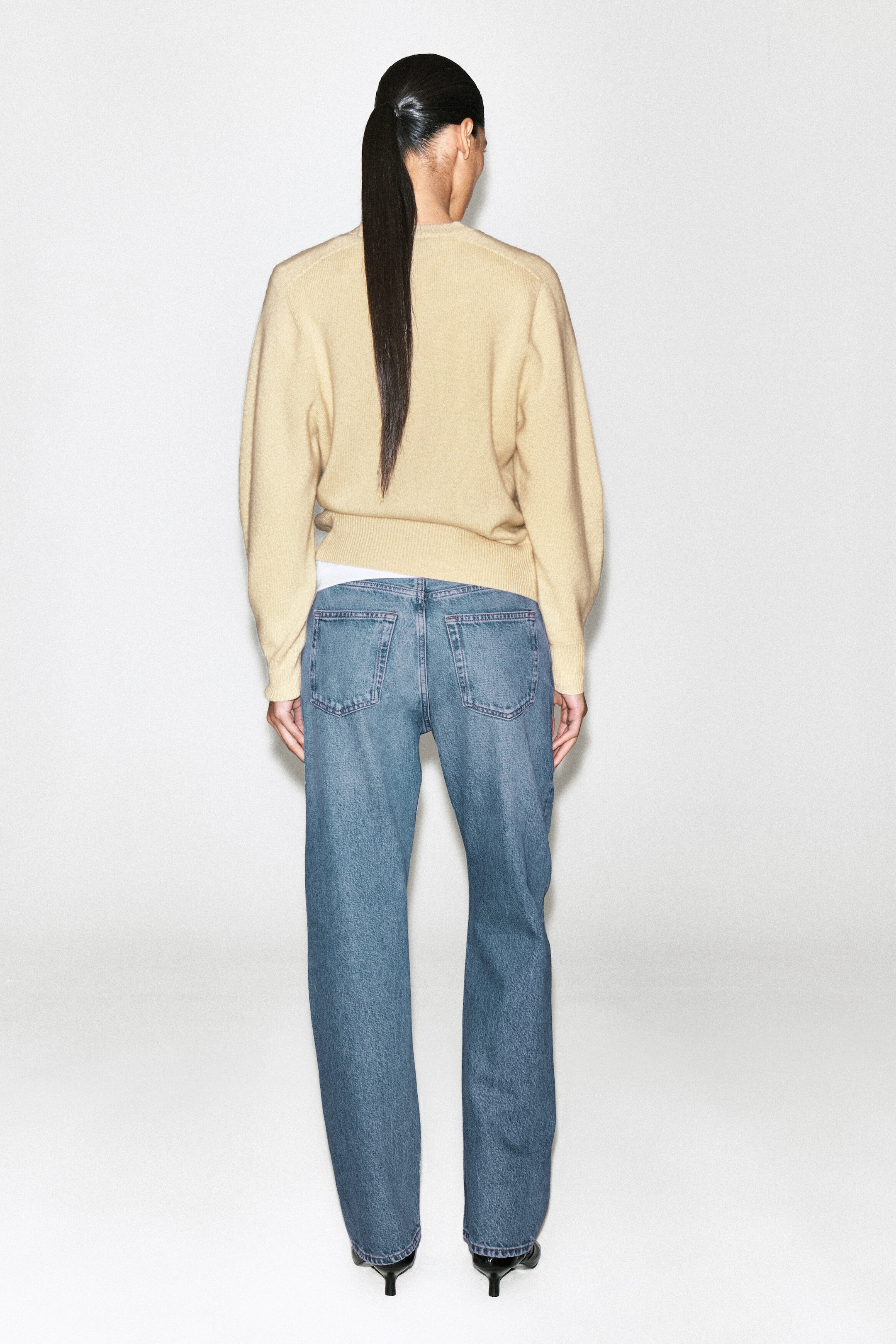 The Chord Straight-Leg Jeans, shown from the back, present a relaxed straight-leg silhouette in a medium blue wash, with two classic rear patch pockets. The jeans are styled with a beige knit jumper that sits just above the waistband to showcase the mid-rise fit. The Chord Straight-Leg Jeans, shown from the back, present a relaxed straight-leg silhouette in a medium blue wash, with two classic rear patch pockets. The jeans are styled with a beige knit jumper that sits just above the waistband to showcase the mid-rise fit.
