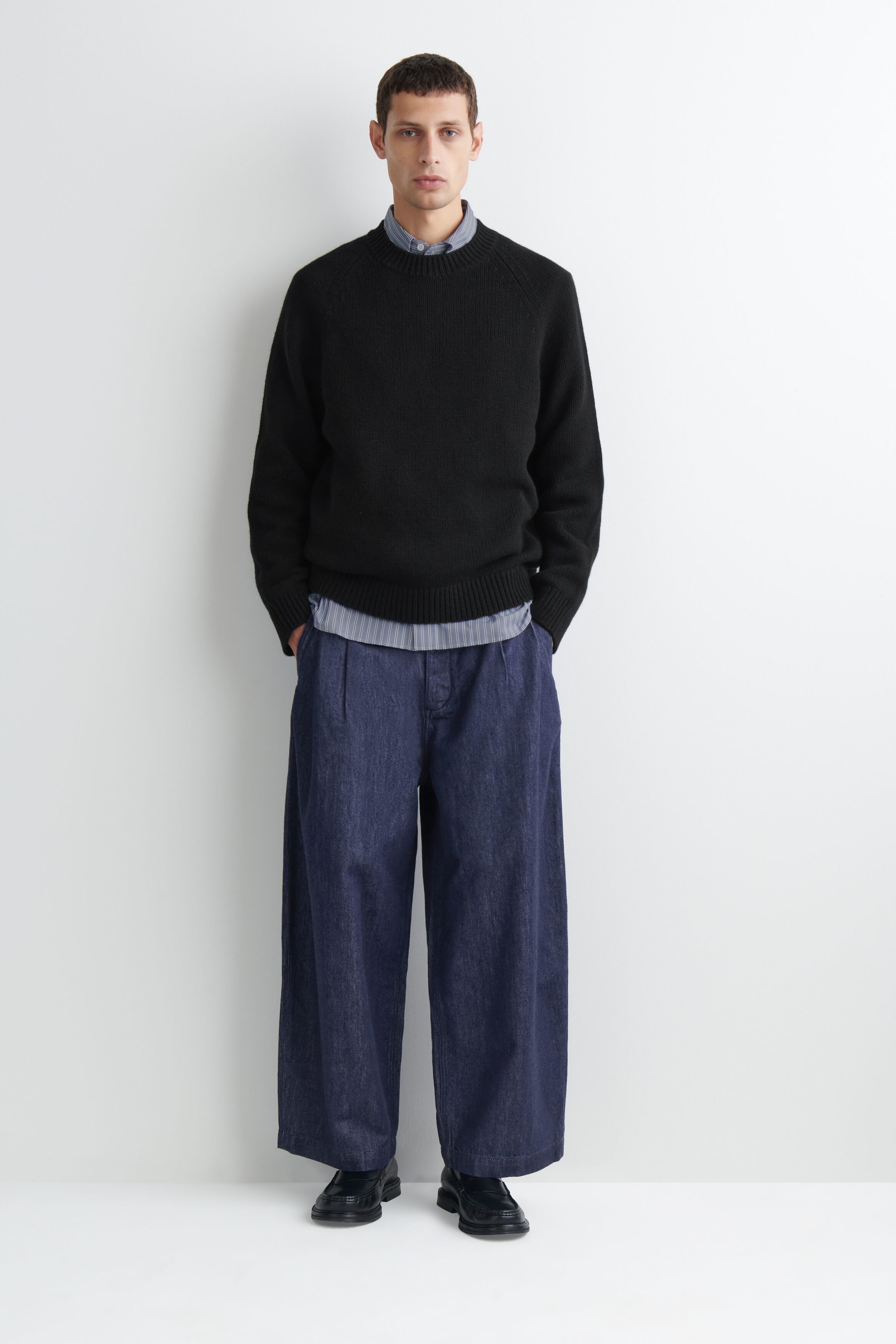 Le pantalon barrel-leg en denim plissé à coupe décontractée, délavage bleu foncé, est présenté de face, avec une taille haute et des plis sur le devant, ainsi qu’une silhouette large aux jambes courbes. Il tombe amplement jusqu’aux chevilles, mettant en valeur son design volumineux et structuré. Le pantalon barrel-leg en denim plissé à coupe décontractée, délavage bleu foncé, est présenté de face, avec une taille haute et des plis sur le devant, ainsi qu’une silhouette large aux jambes courbes. Il tombe amplement jusqu’aux chevilles, mettant en valeur son design volumineux et structuré.